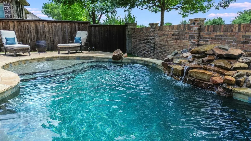 Freeform swimming pool with integrated rock waterfall feature