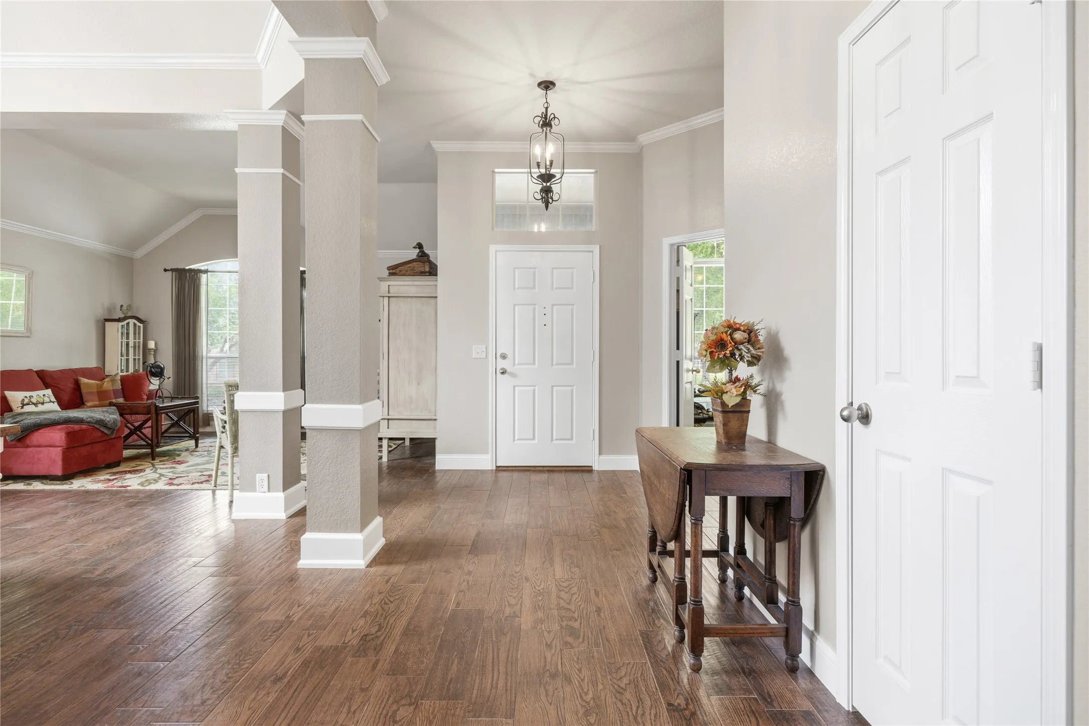 Entryway featuring wood-finish flooring, white paneled doors, and crown molding