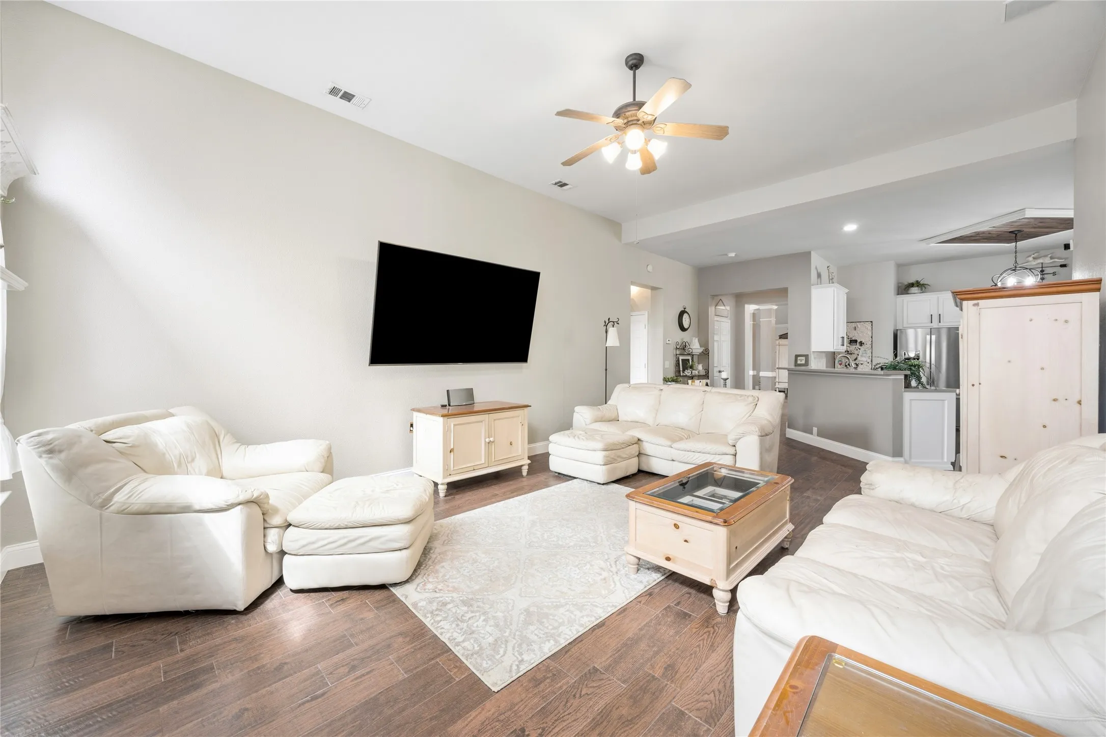 Spacious living area featuring wood-finish flooring, vaulted ceilings, and a ceiling fan