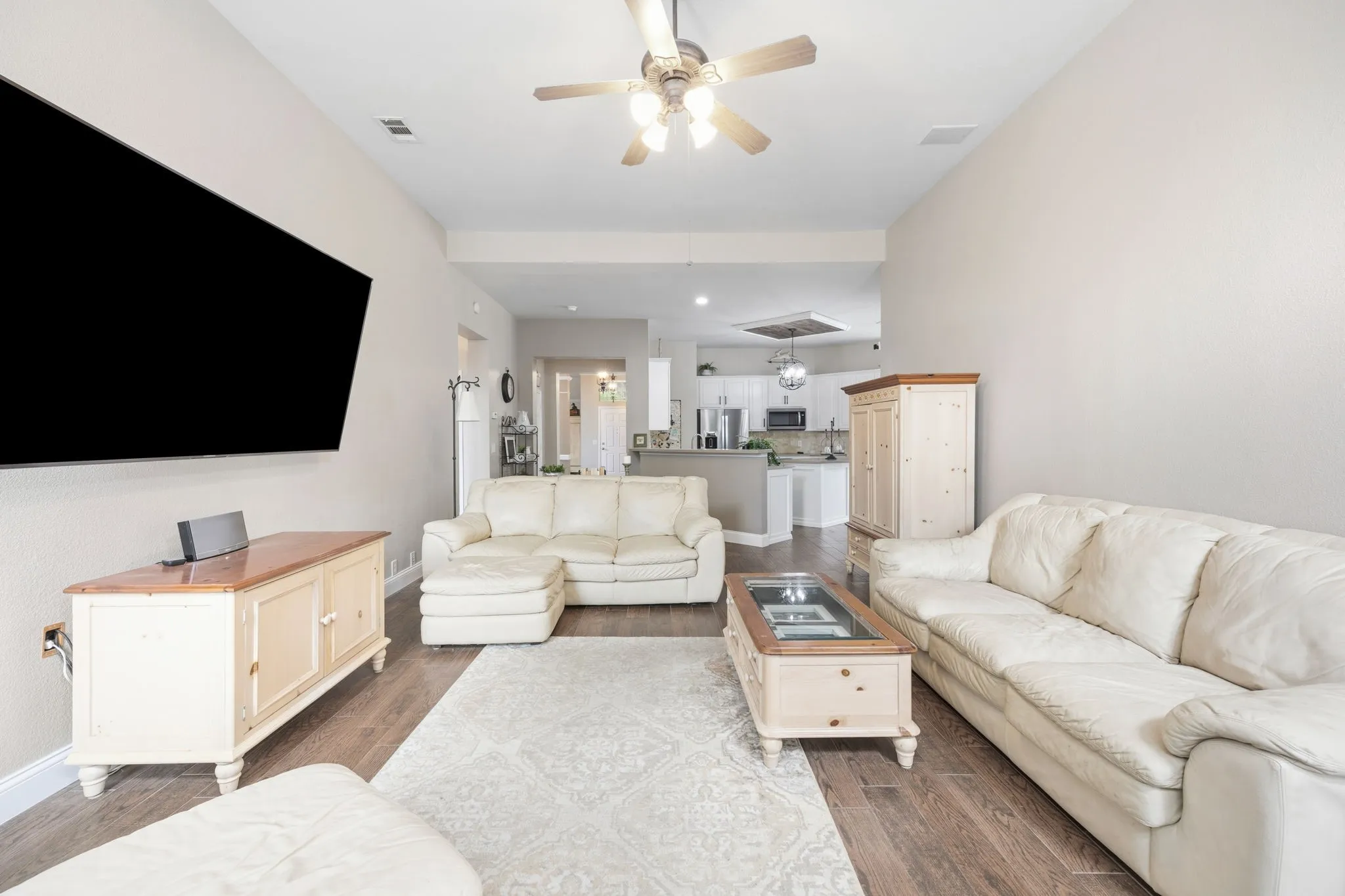Spacious living area featuring wood-finish flooring, vaulted ceilings, and a ceiling fan