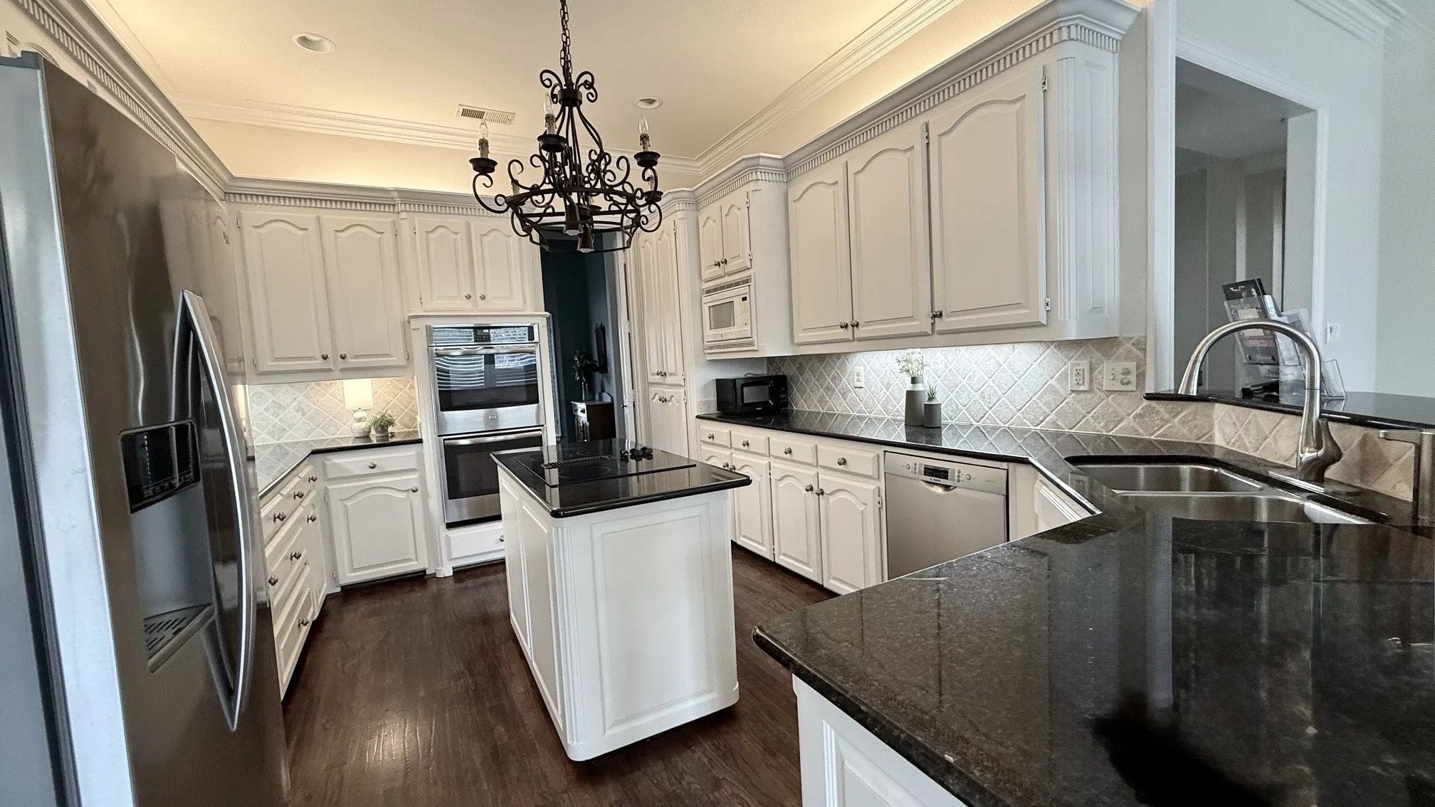 White cabinetry with plenty of cabinet space. Granite counters and breakfast bar. SS double ovens, refrigerator, and a smooth cook-top in the island.
