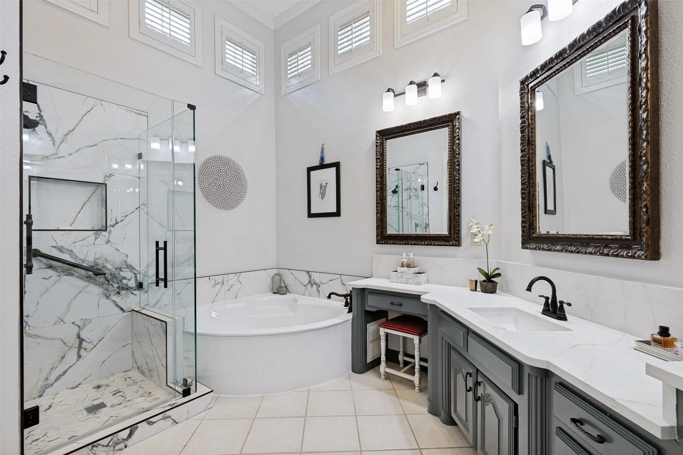 The remodeled Primary Bath is spa-like with a frameless glass door and tile covered shower, plus a romantic corner tub. Stylish updated lighting, and framed mirrors. Light and bright with high soaring ceilings.