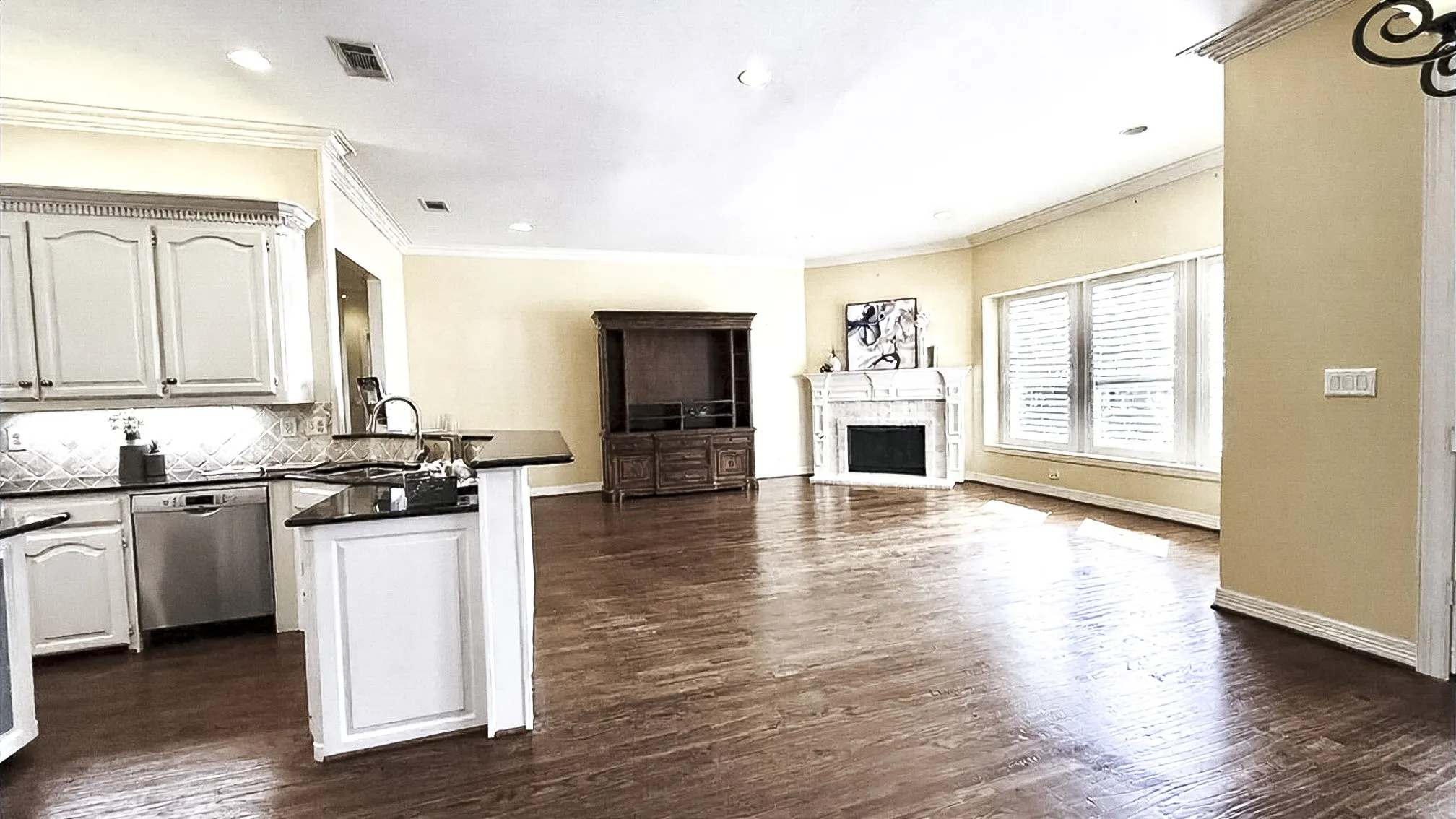 his beautiful open-concept living space features a corner fireplace, high ceilings, and a wall of windows that fill the room with natural light. The area flows seamlessly from the hardwood-floored living area to a casual dining space, which opens through double doors to a covered patio. The private backyard overlooks a lush greenbelt.