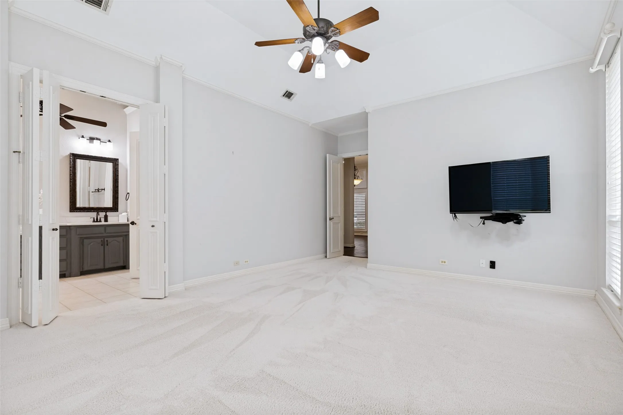 The primary bedroom has multiple spaces for furniture and spaces to relax.  A light filled room with fluffy white carpet, plantation shutters and great backyard views.