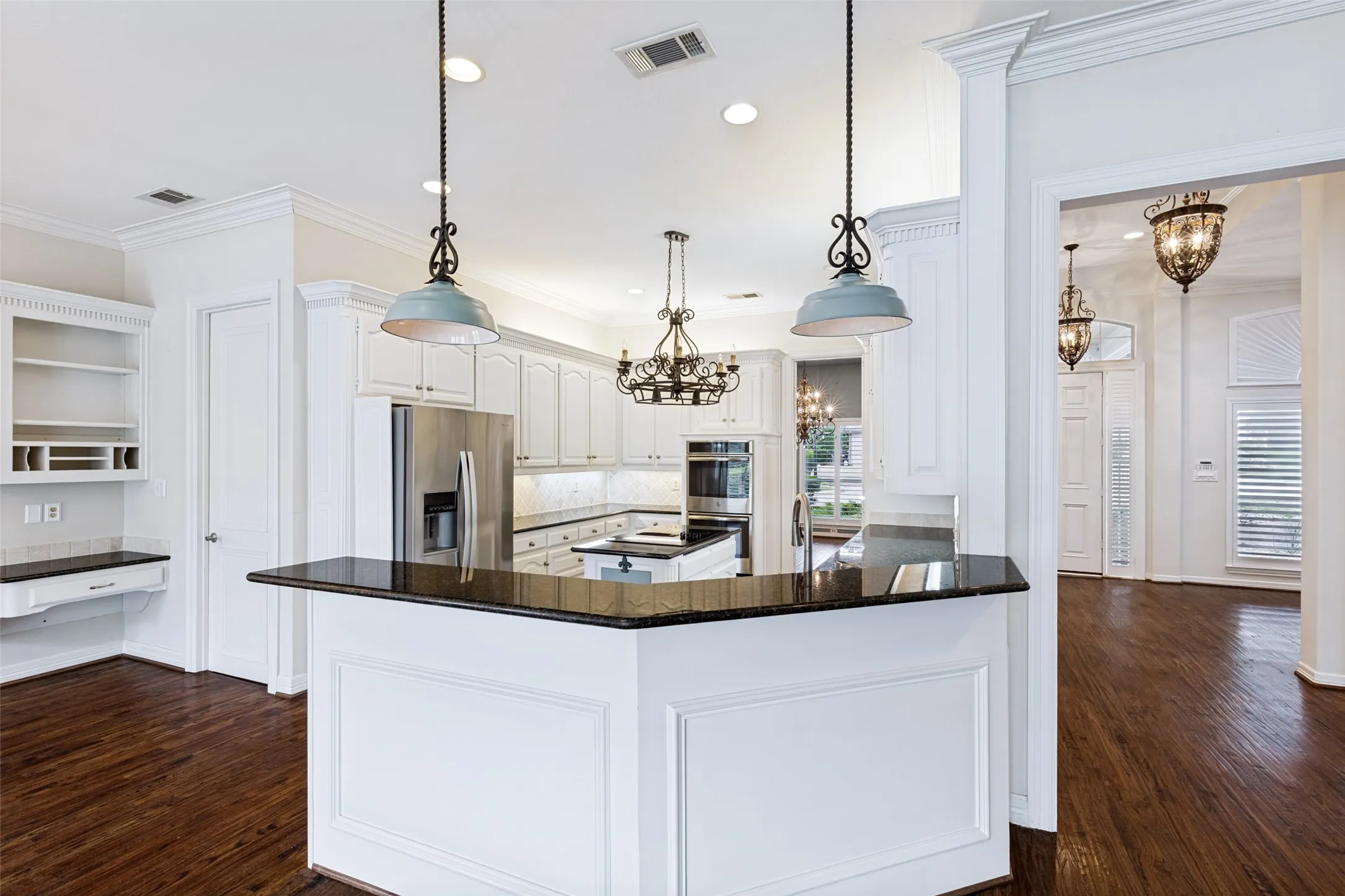View of the built-in kitchen planning area, breakfast bar, kitchen and entry to the foyer and formal living.