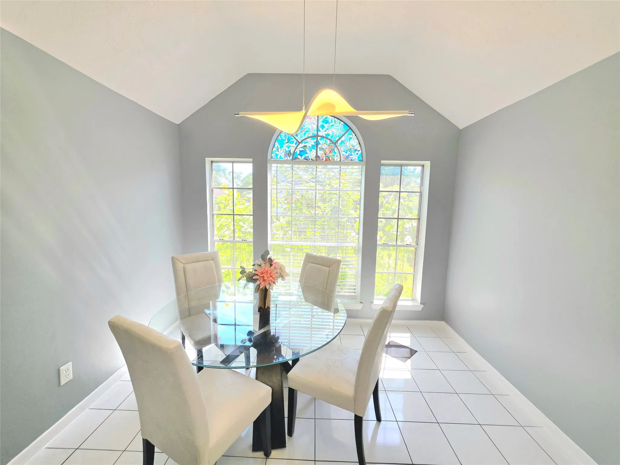 Room featuring a vaulted ceiling and an arched window with stained glass detailing