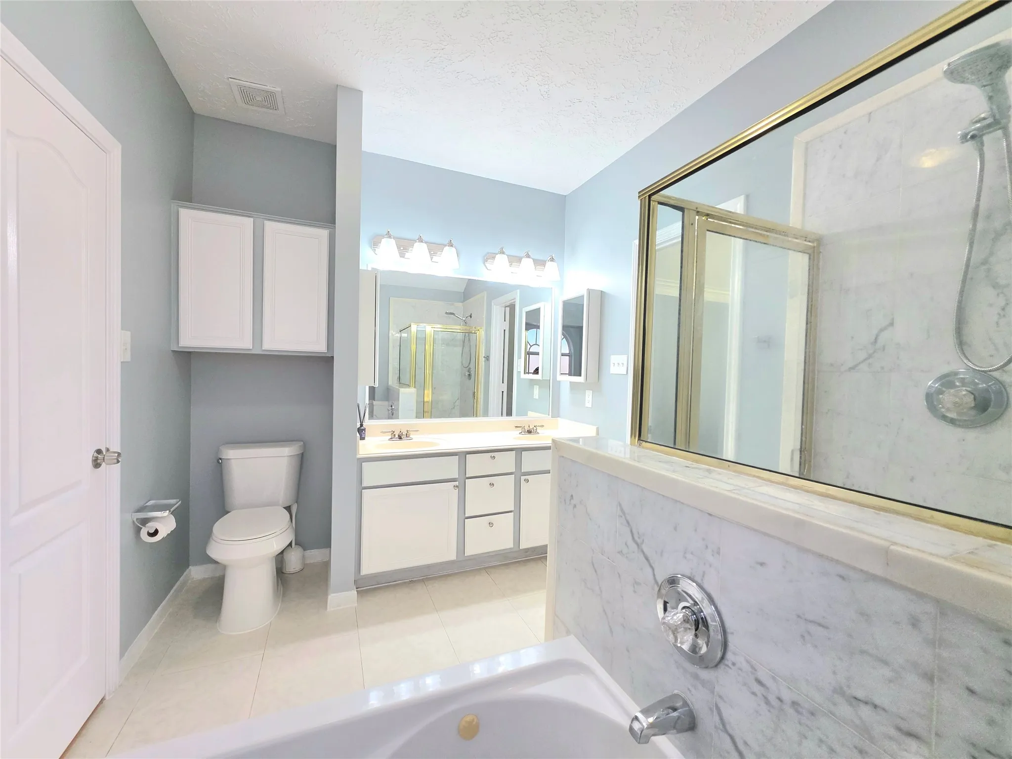 Bathroom featuring a built-in tub, separate shower with glass enclosure, and double vanity