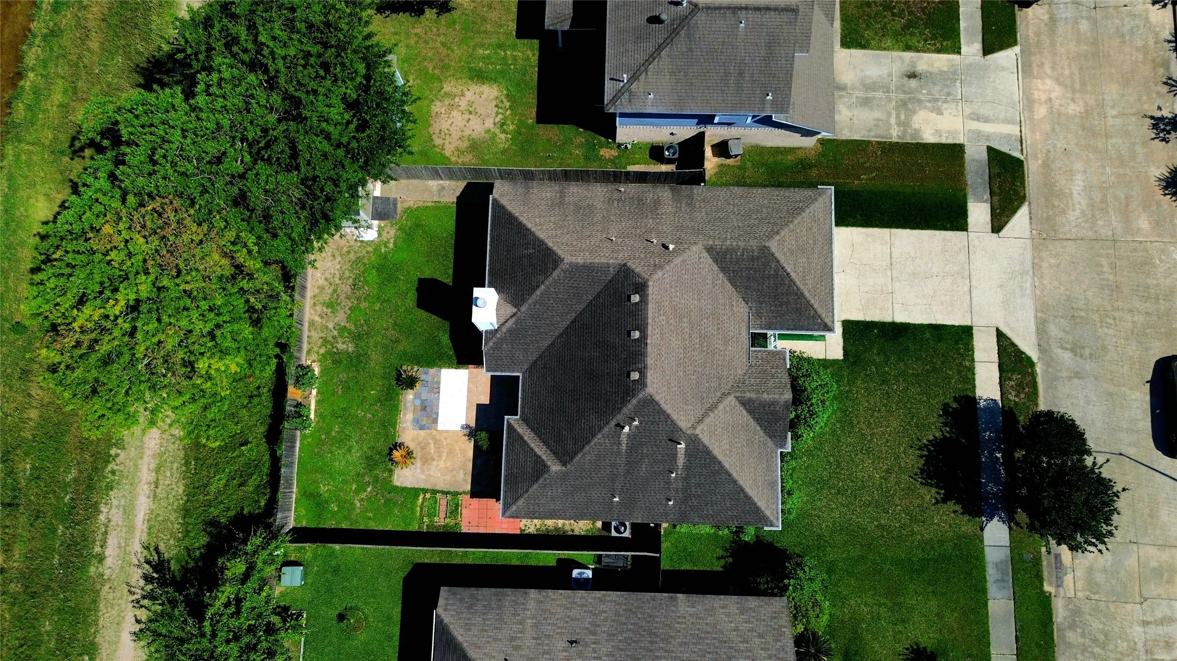 Aerial view showcasing a residential property with a multi-gabled roof and a concrete driveway