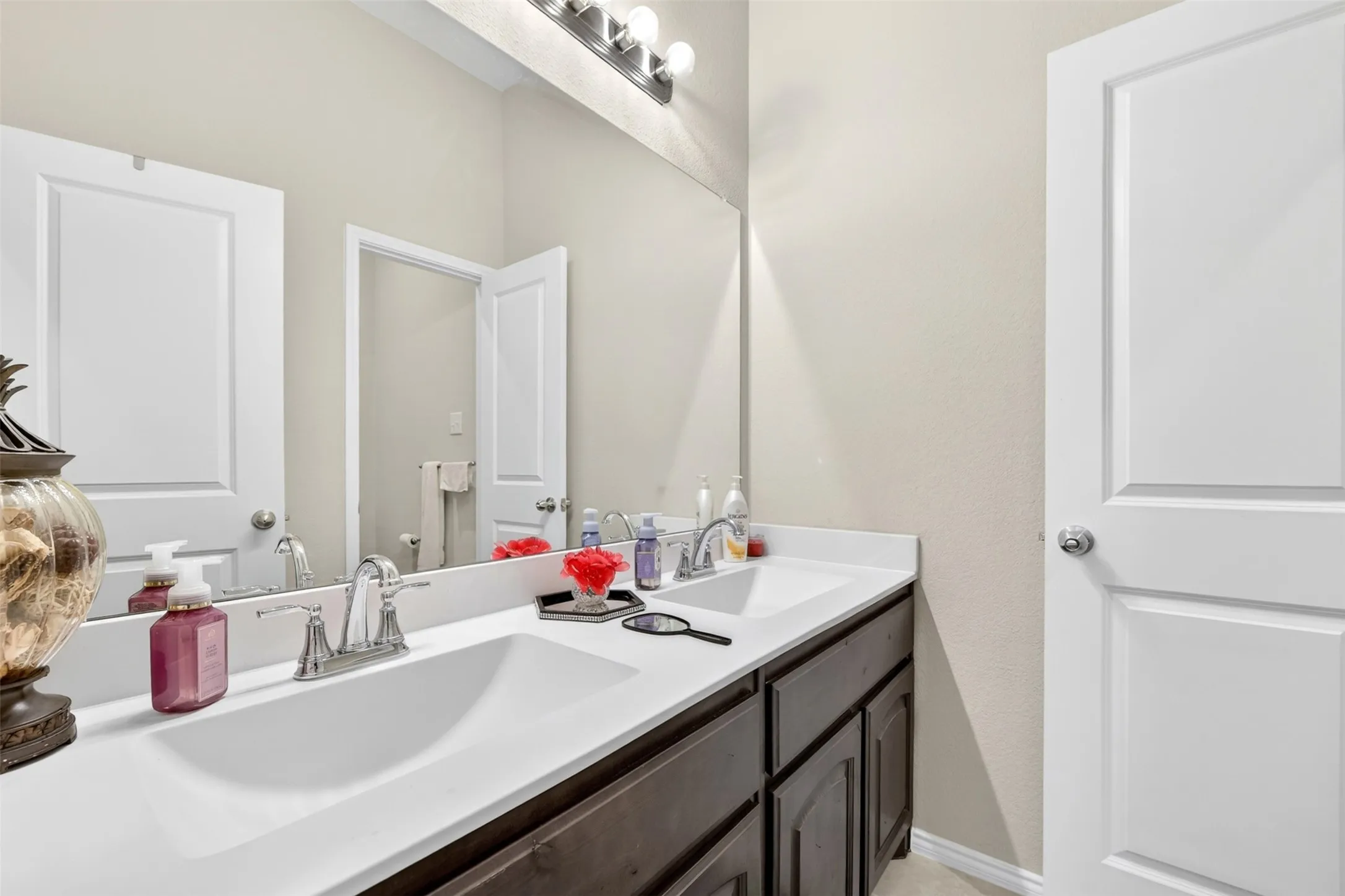 Double vanity with integrated sinks, white countertops, and dark wood-finish cabinetry