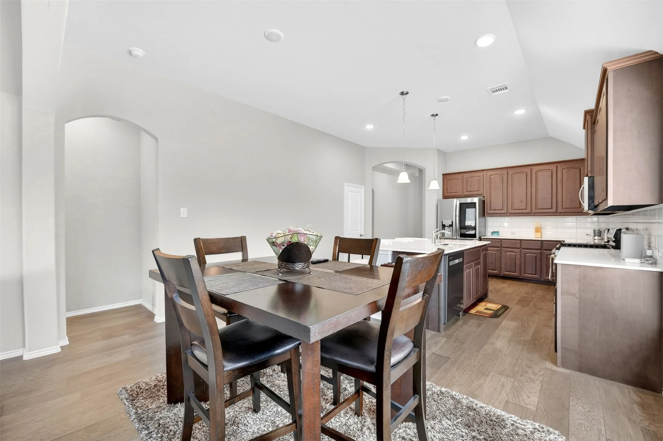 Open-concept kitchen and dining area featuring wood-finish flooring, recessed lighting, and a kitchen island with pendant lighting