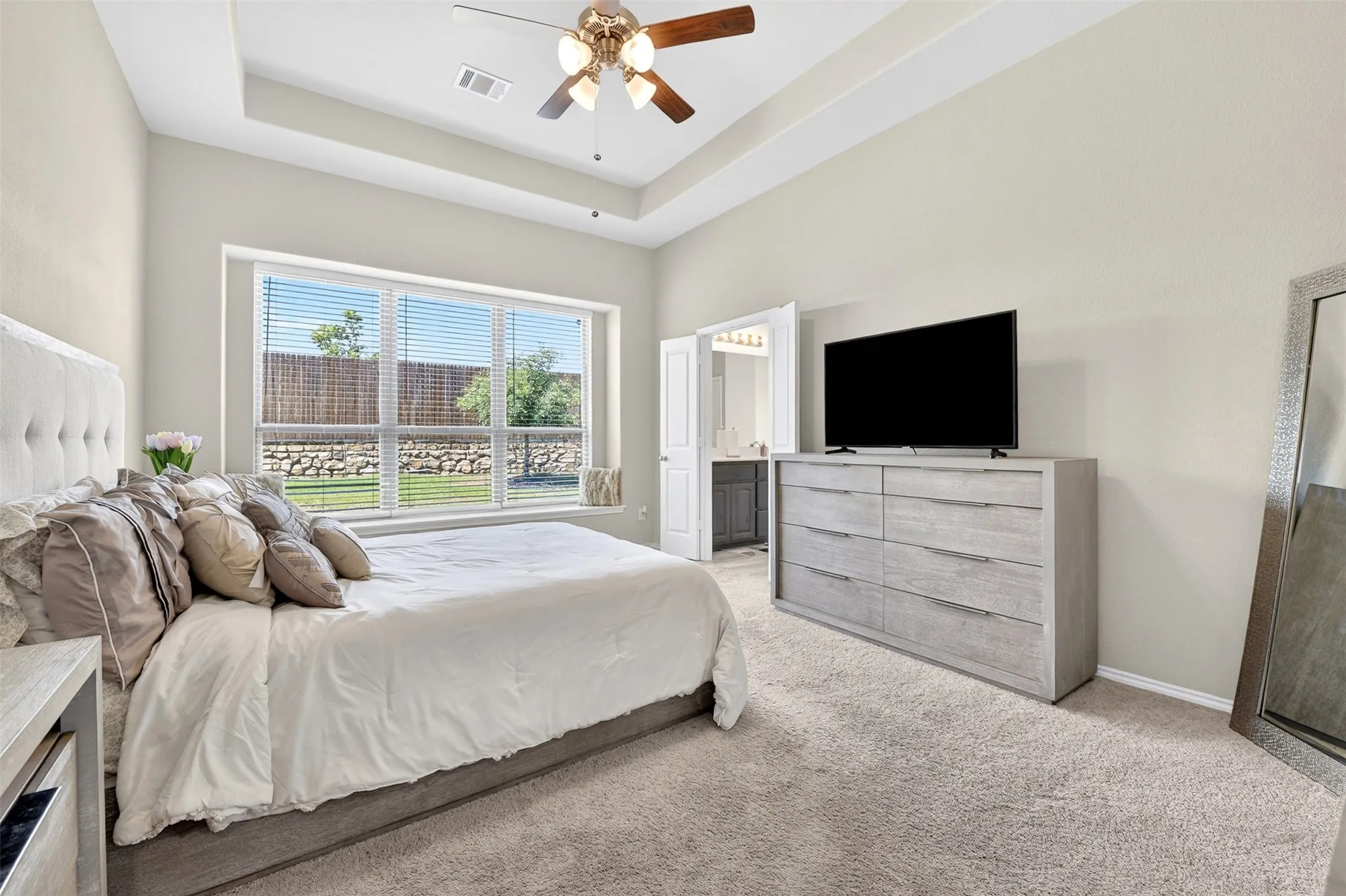 Spacious bedroom featuring a tray ceiling, recessed lighting, and a ceiling fan with light fixture
