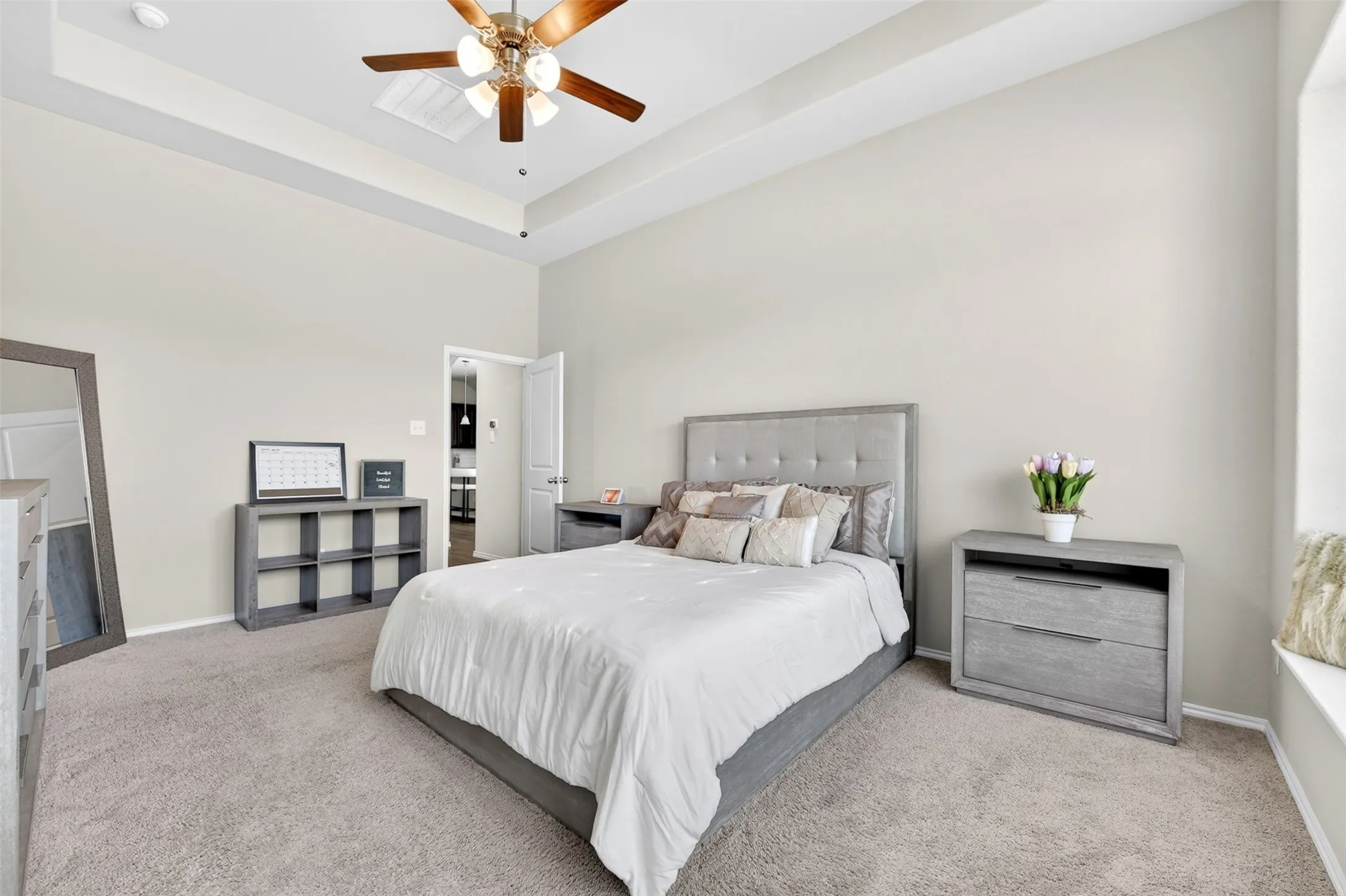 Spacious room featuring tray ceilings, neutral wall tones, and light gray carpet flooring