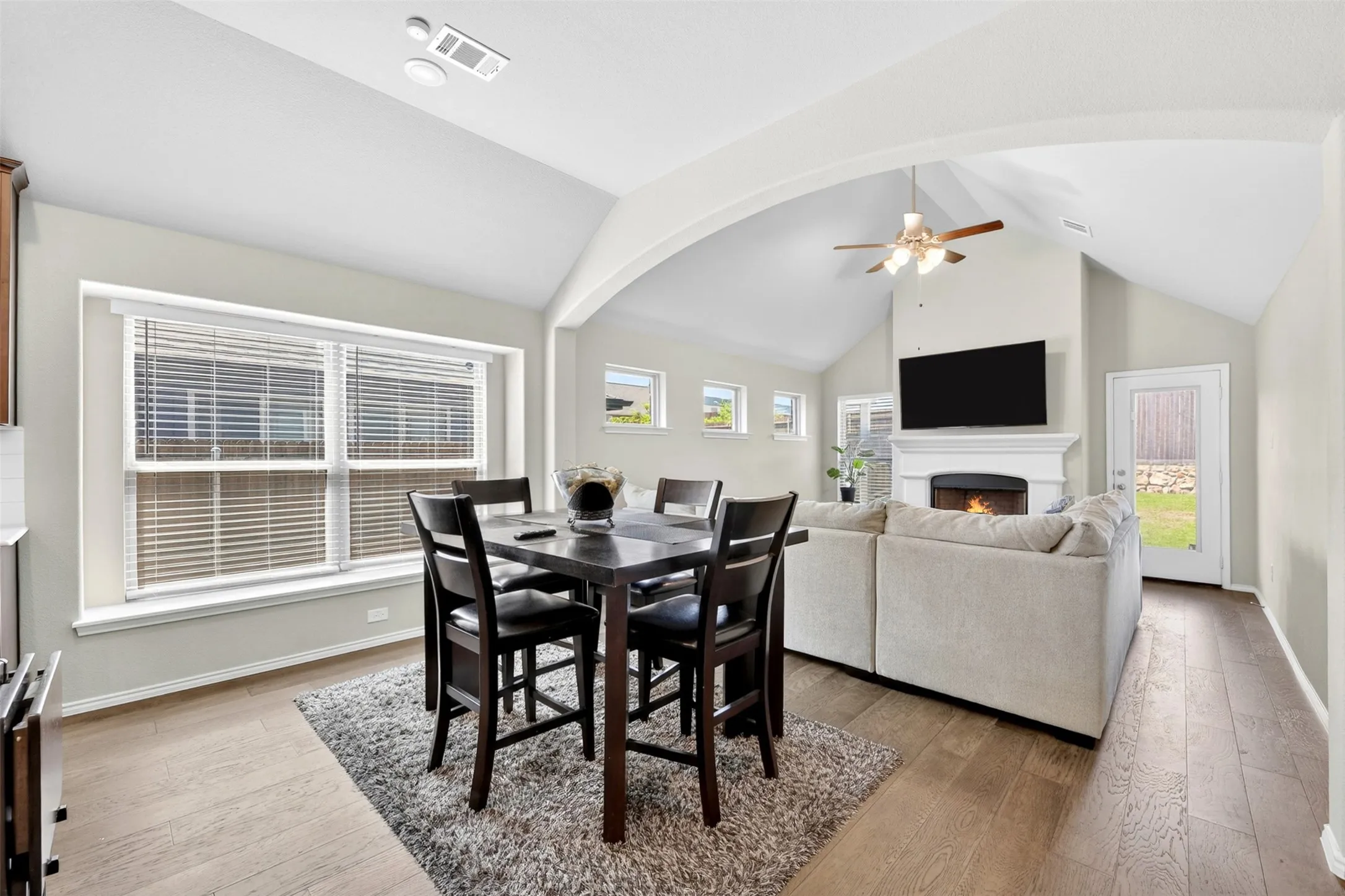 Open-concept living space featuring vaulted ceilings, wood-finish flooring, and an arched entryway