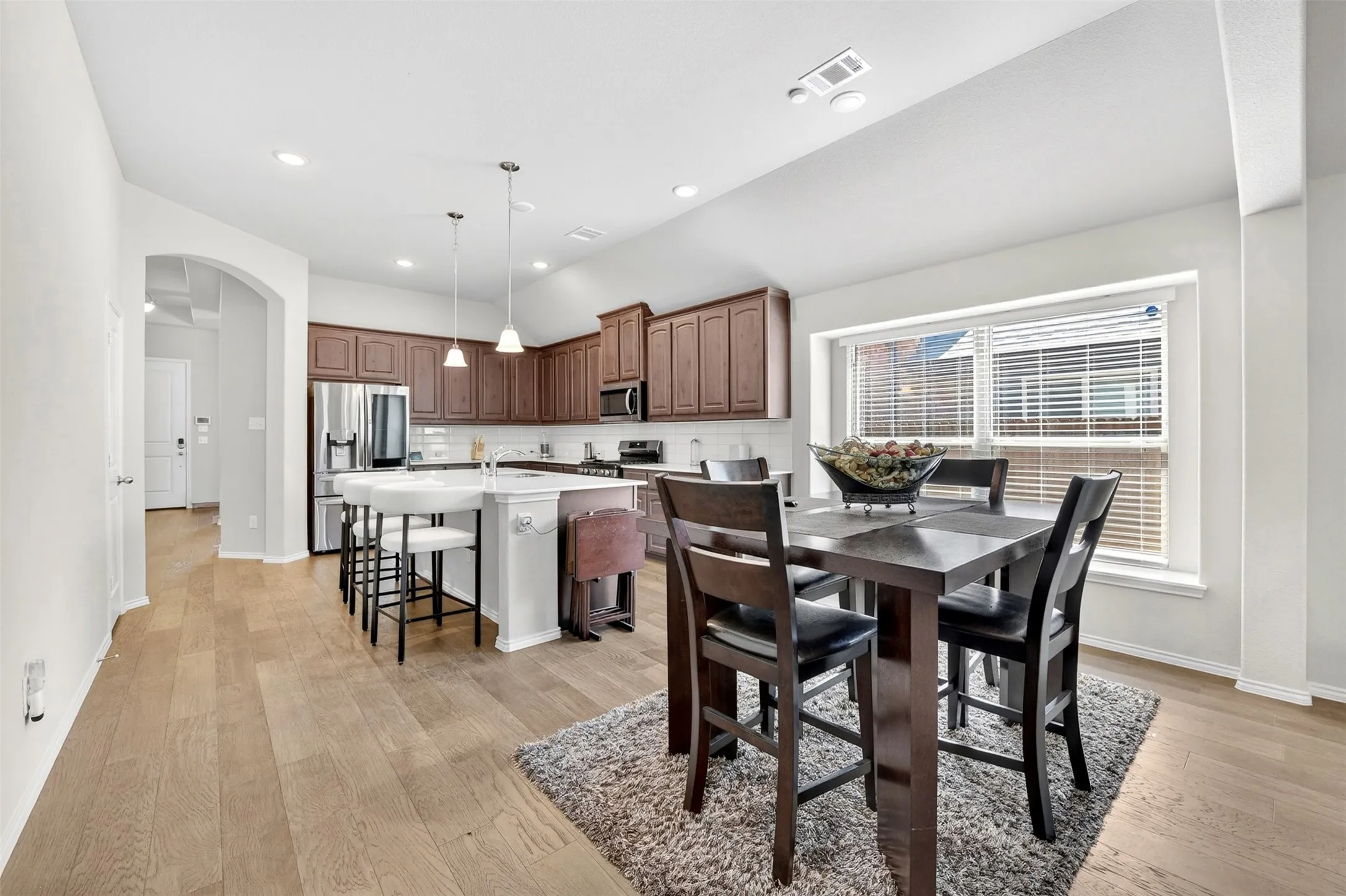 Kitchen featuring a center island with bar seating, stainless steel appliances, dark wood-finish cabinetry, and recessed lighting