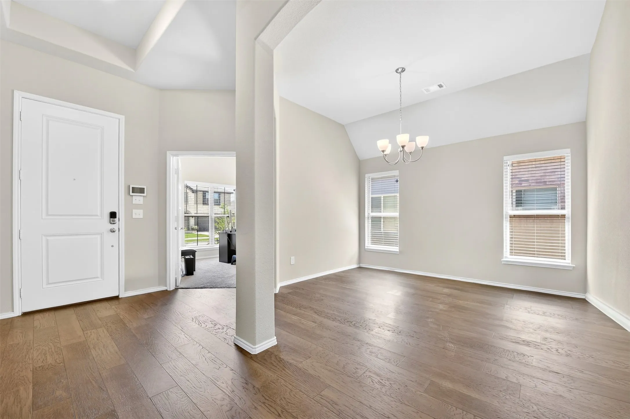 Entryway and adjacent room featuring wood-finish flooring, vaulted ceiling, and recessed lighting
