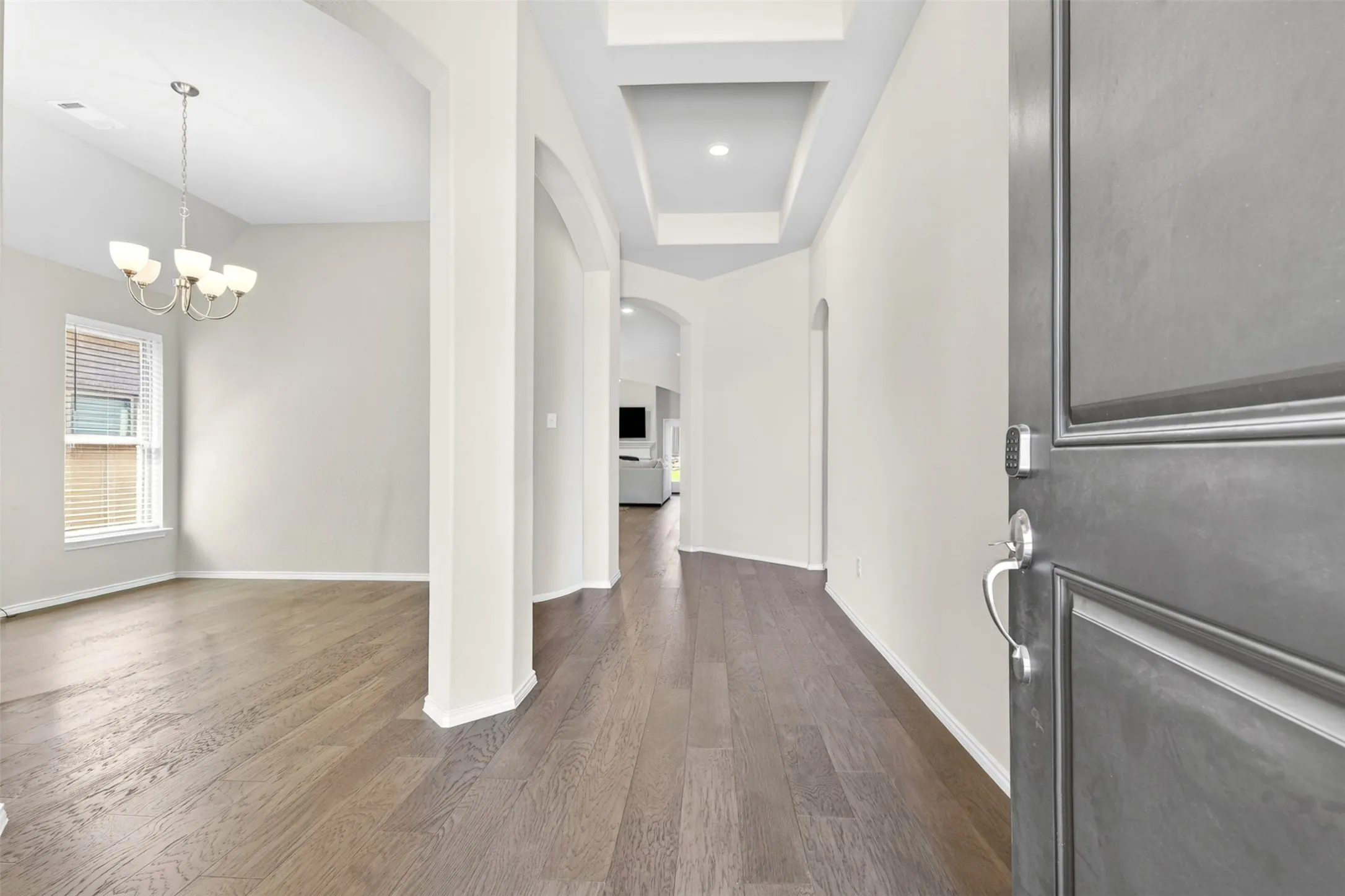 Entryway featuring wood-finish flooring, a tray ceiling, and arched doorways