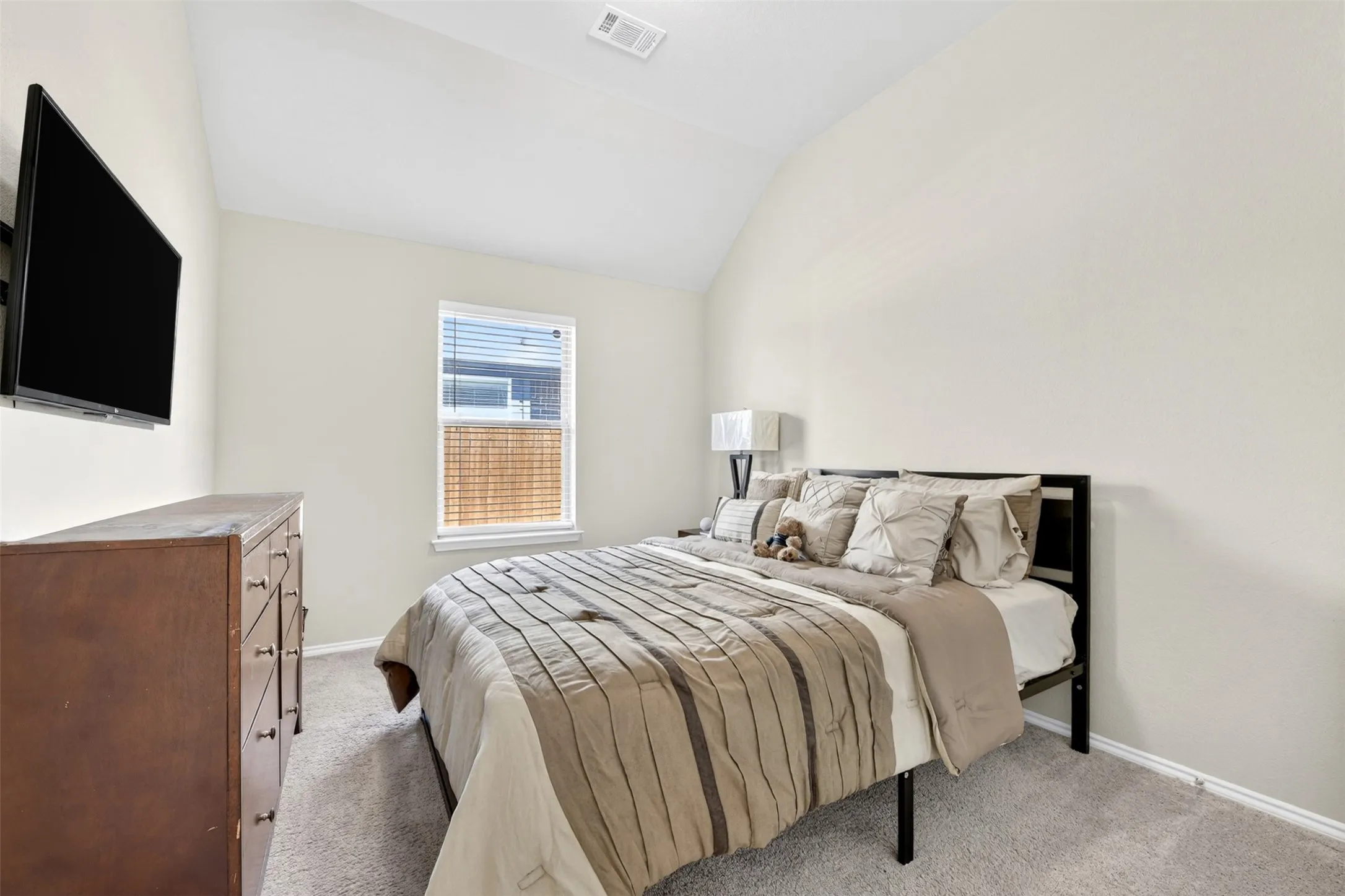 Carpeted interior space with a vaulted ceiling and neutral wall tones