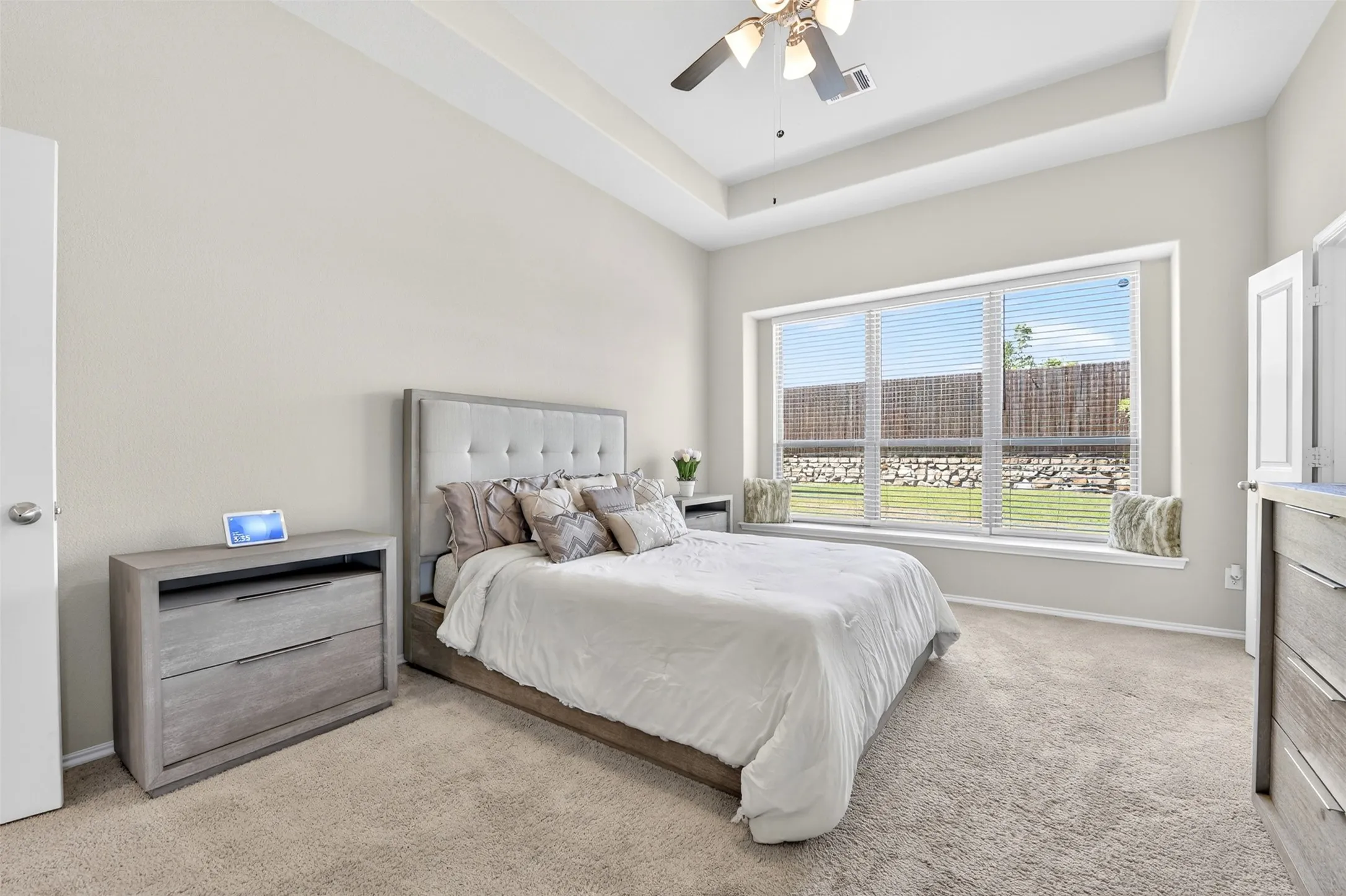 Bedroom featuring light-colored carpeting, a tray ceiling, and a ceiling fan with integrated lighting