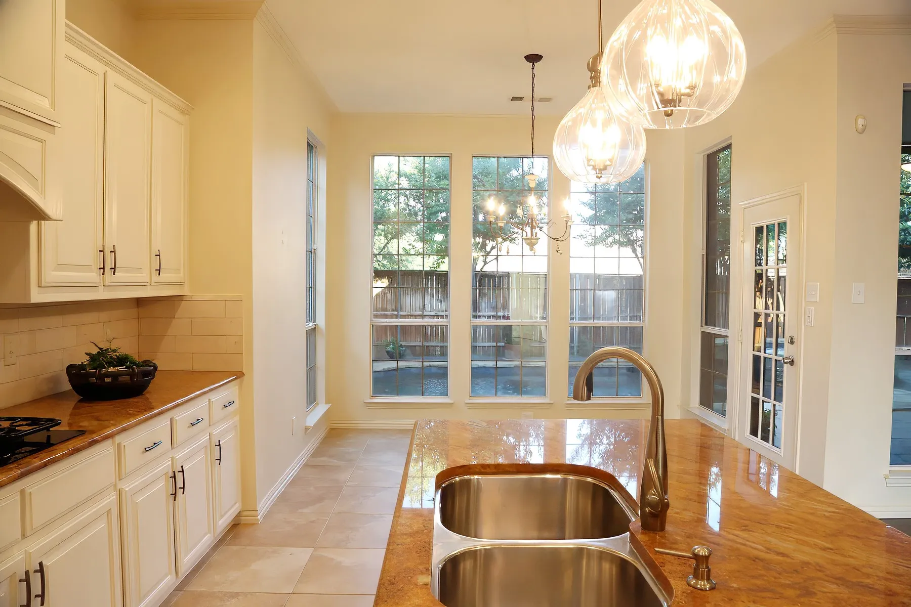 Kitchen featuring an expansive island with a double stainless steel sink and a gooseneck faucet