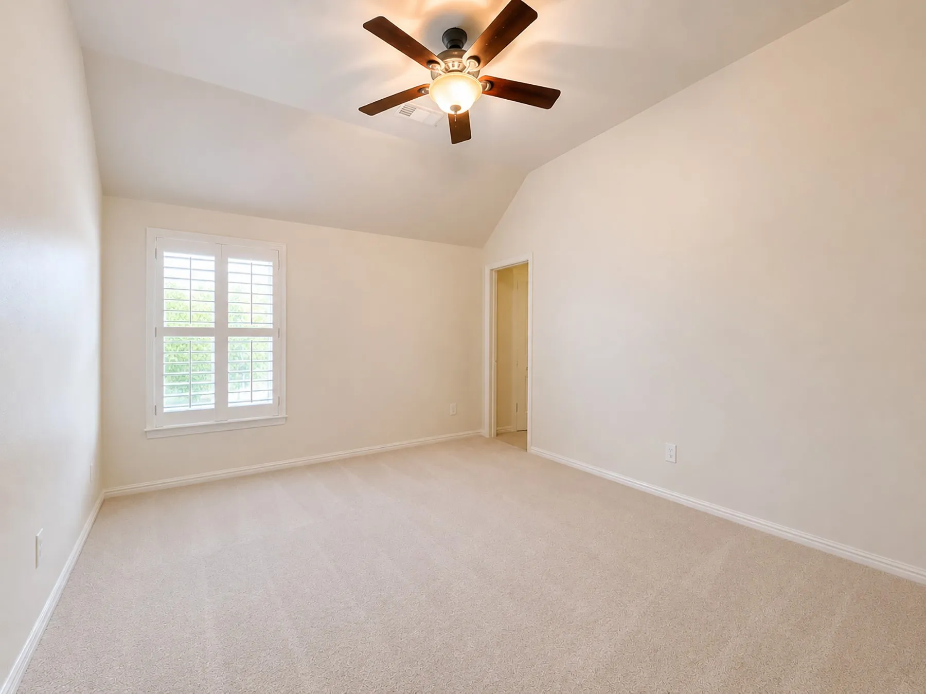 Another lovely oversized bedroom with plantation shutters, new carpeting, and fresh paint. Ceiling fan with integrated lighting assists during the Texas heat.