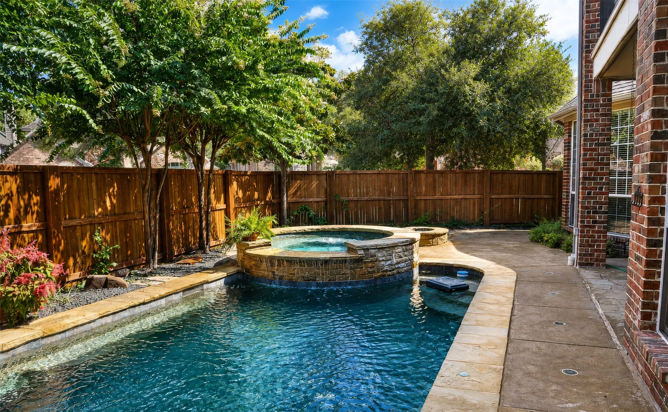 Backyard swimming pool with an integrated spa, stone coping, and a waterfall feature