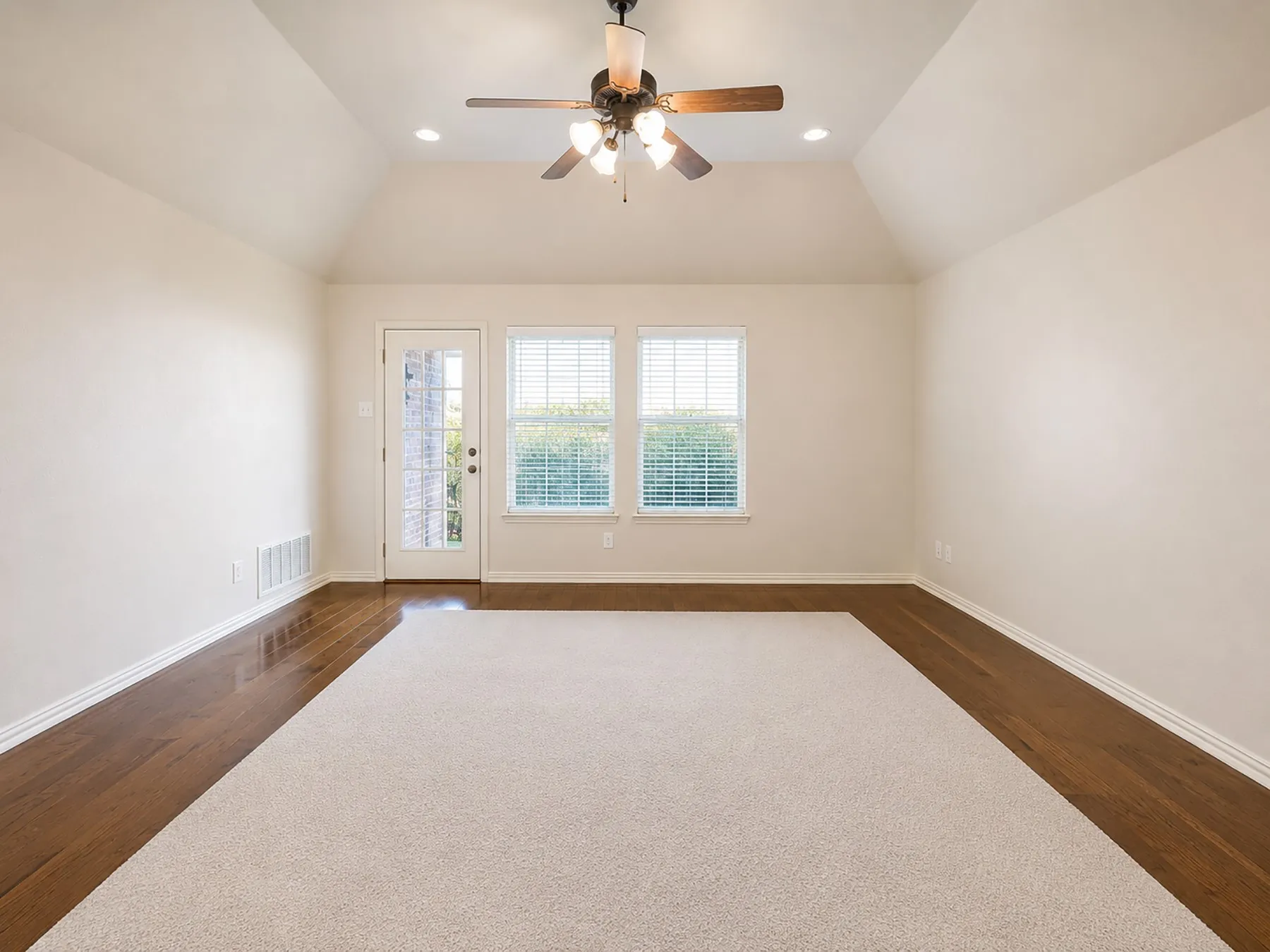 Stairway leads to the game room area featuring vaulted ceiling and door to spacious covered balcony with railing.