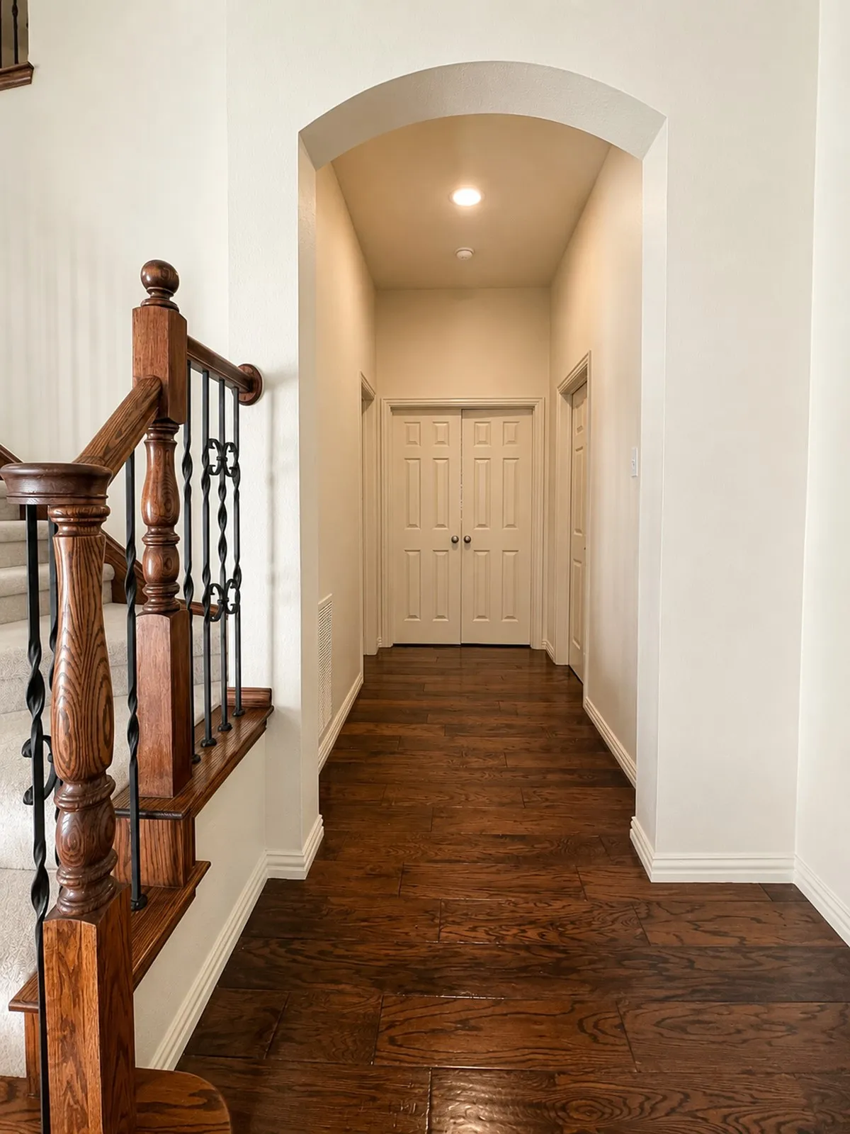 Hallway featuring wood-finish flooring and an arched entryway