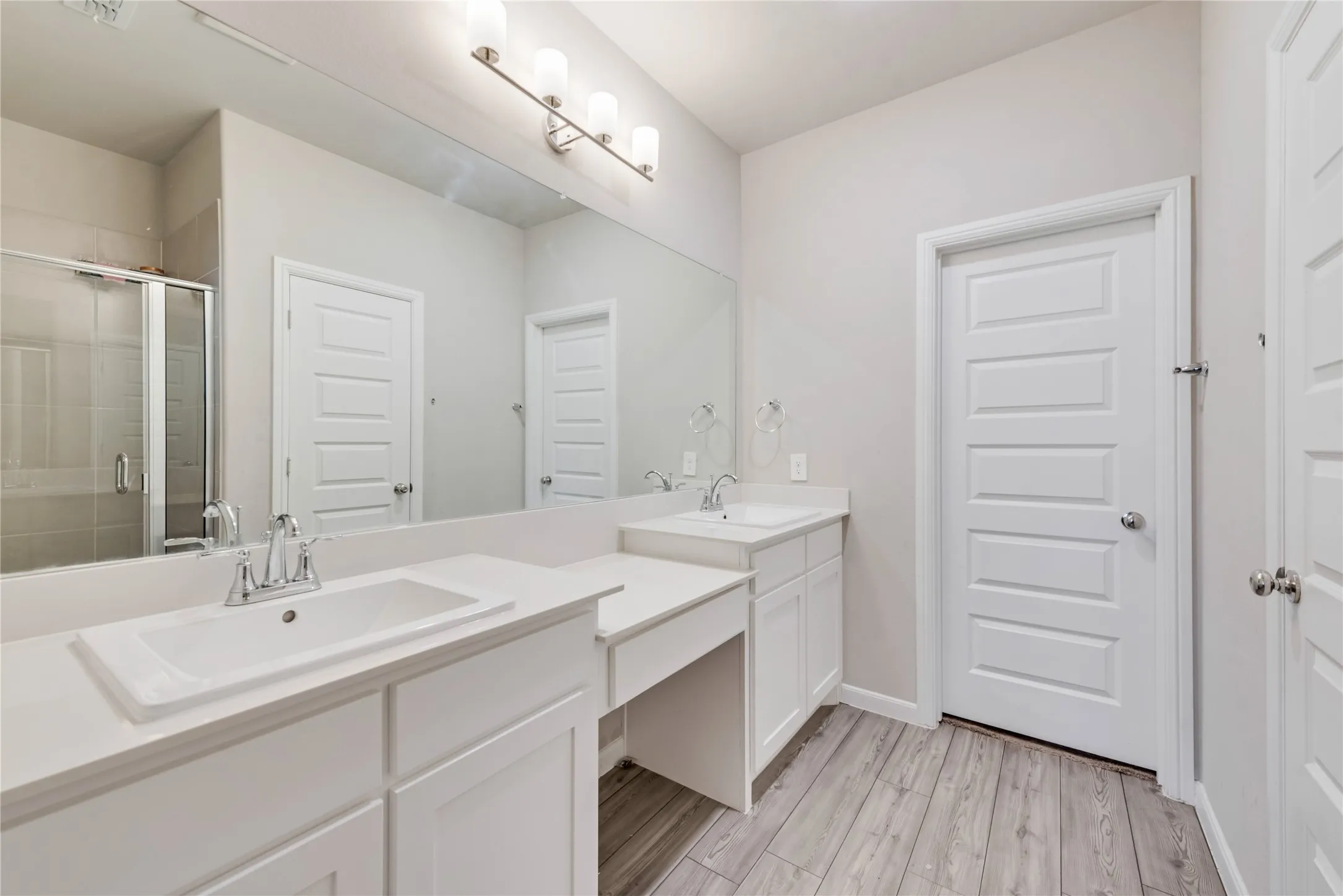 Full bath featuring vanity, baseboards, a stall shower, and wood finished floors