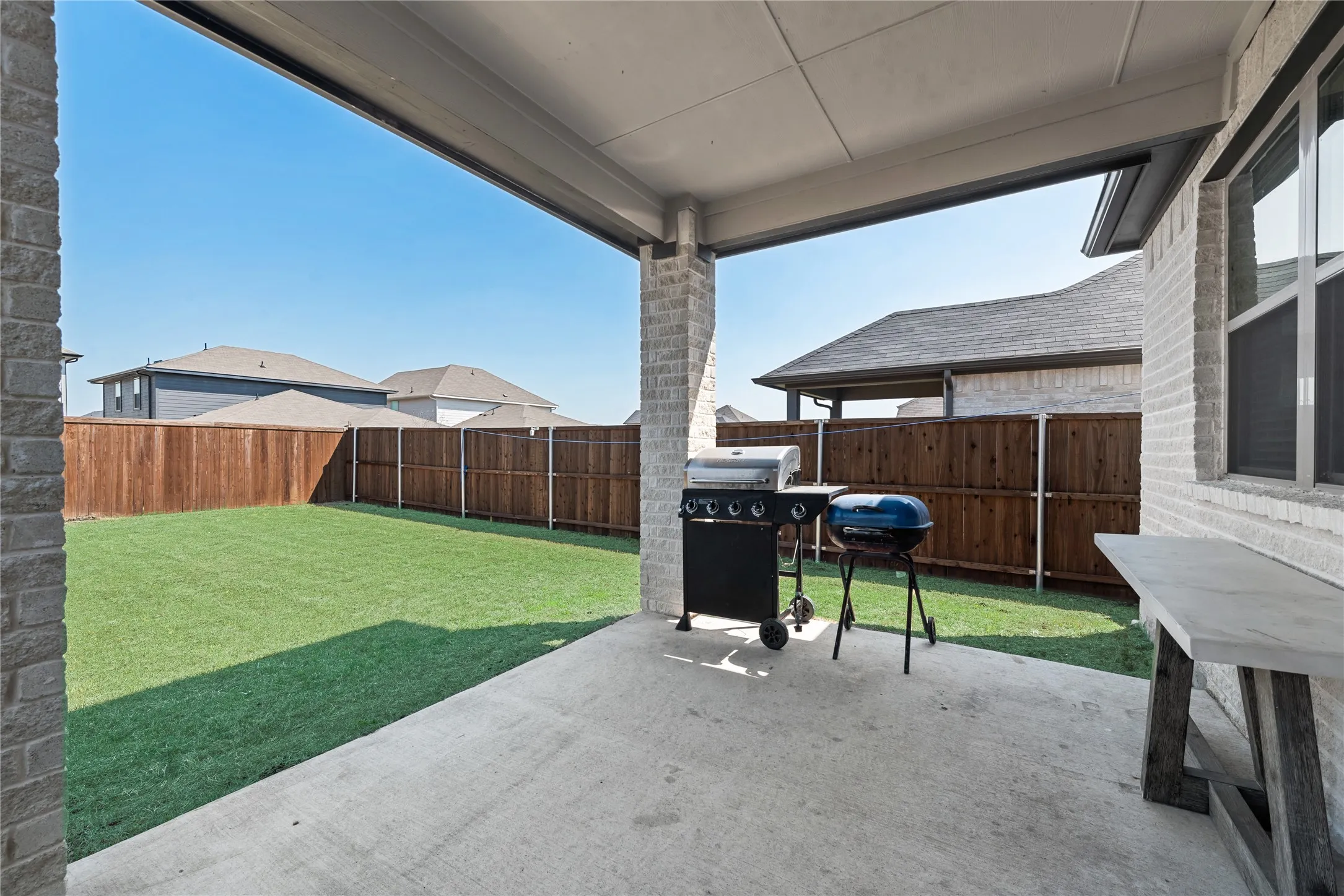 View of patio with a fenced backyard and a grill