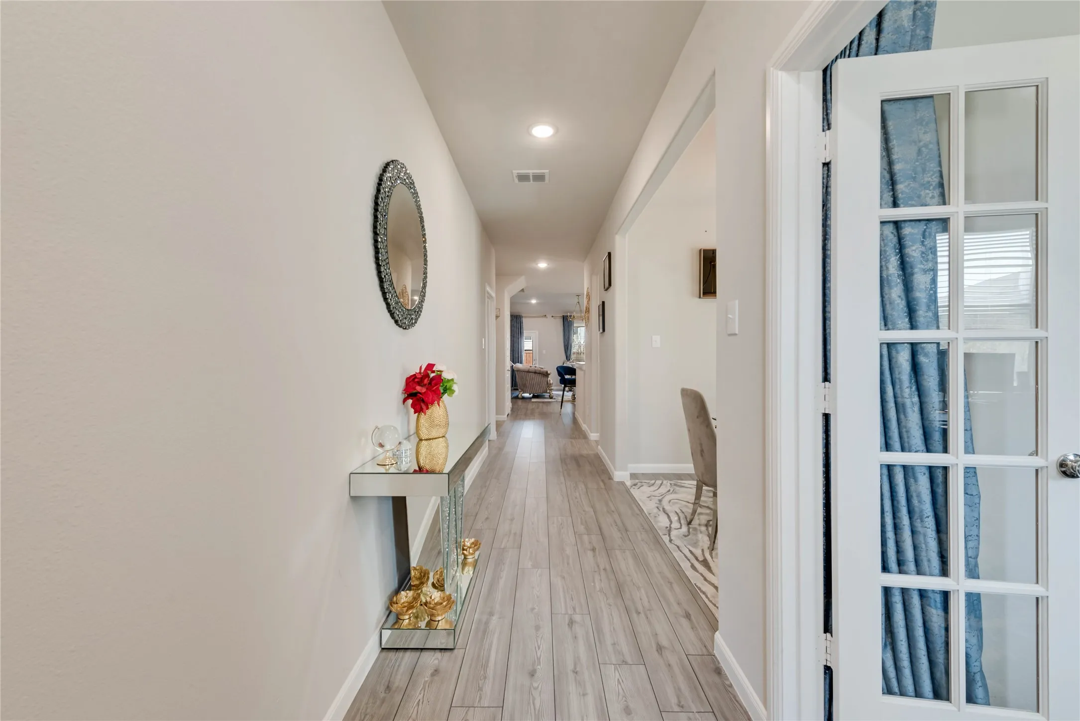 Hall featuring light wood-style floors, baseboards, visible vents, and recessed lighting
