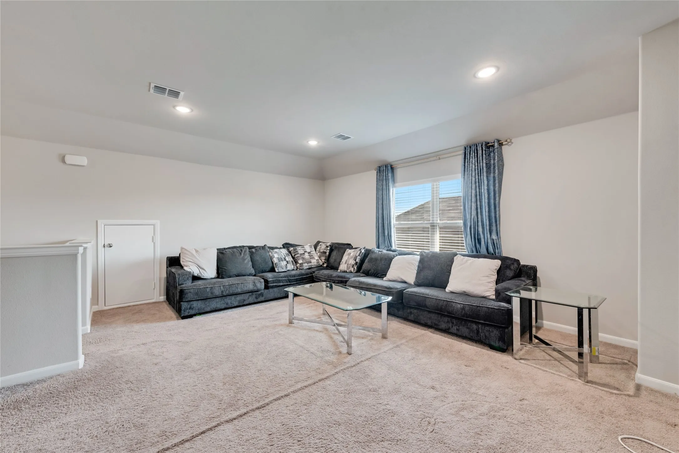 Carpeted living room featuring baseboards, visible vents, and recessed lighting