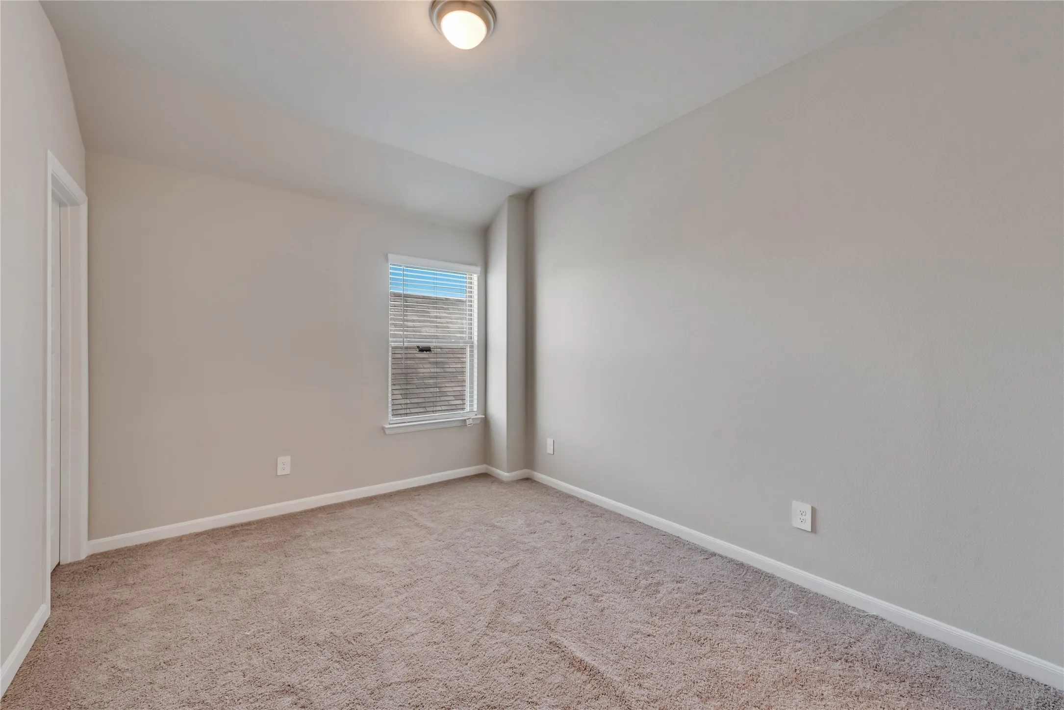 Spare room featuring carpet flooring, baseboards, and lofted ceiling