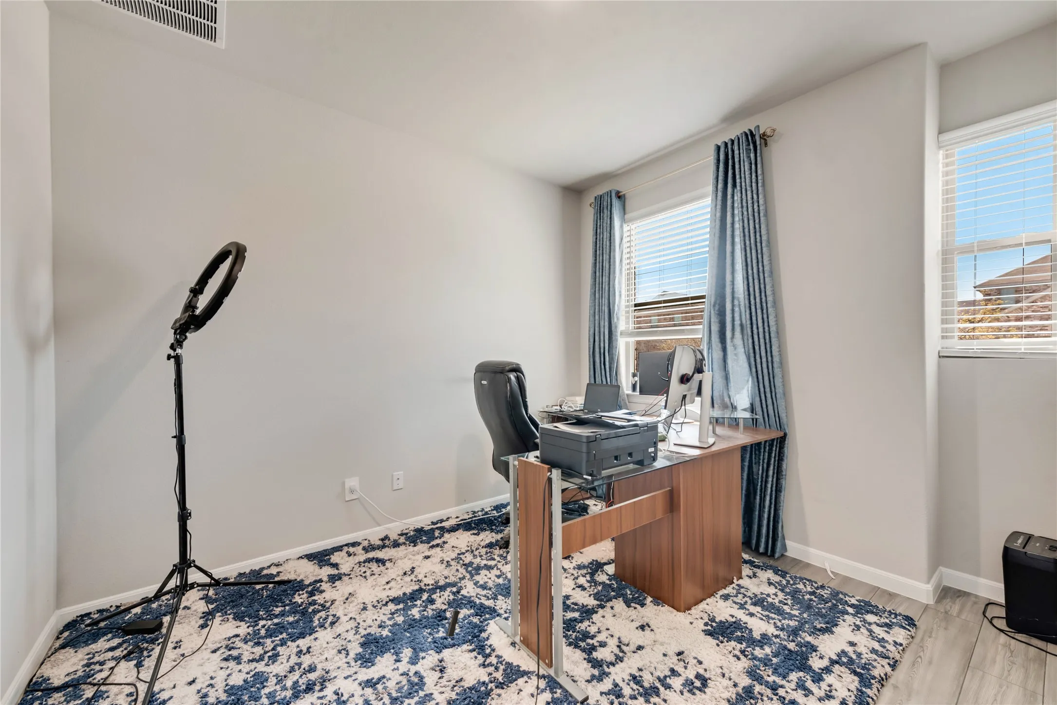 Office space featuring visible vents, a wealth of natural light, light wood finished floors, and baseboards