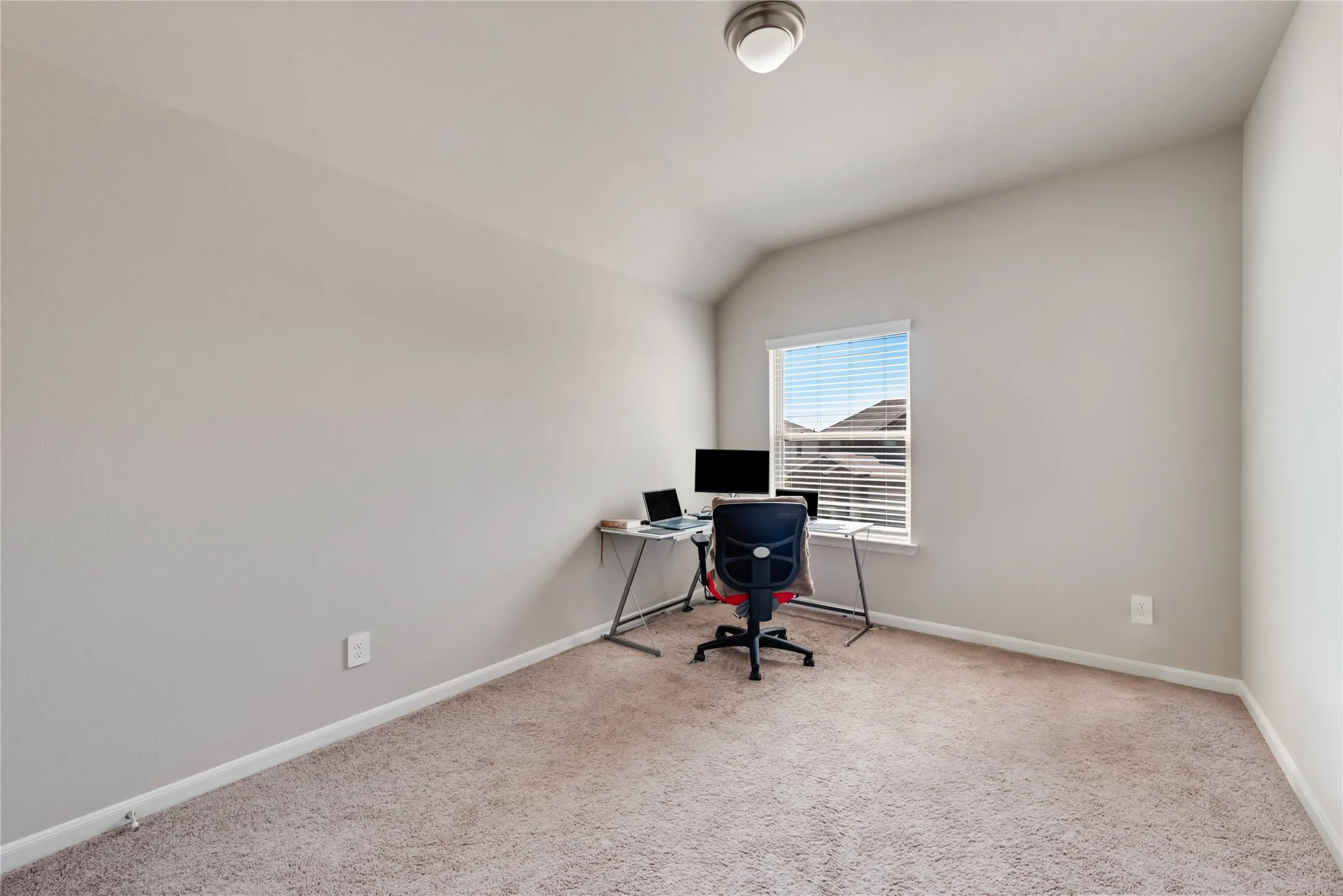 Home office featuring baseboards, carpet flooring, and vaulted ceiling