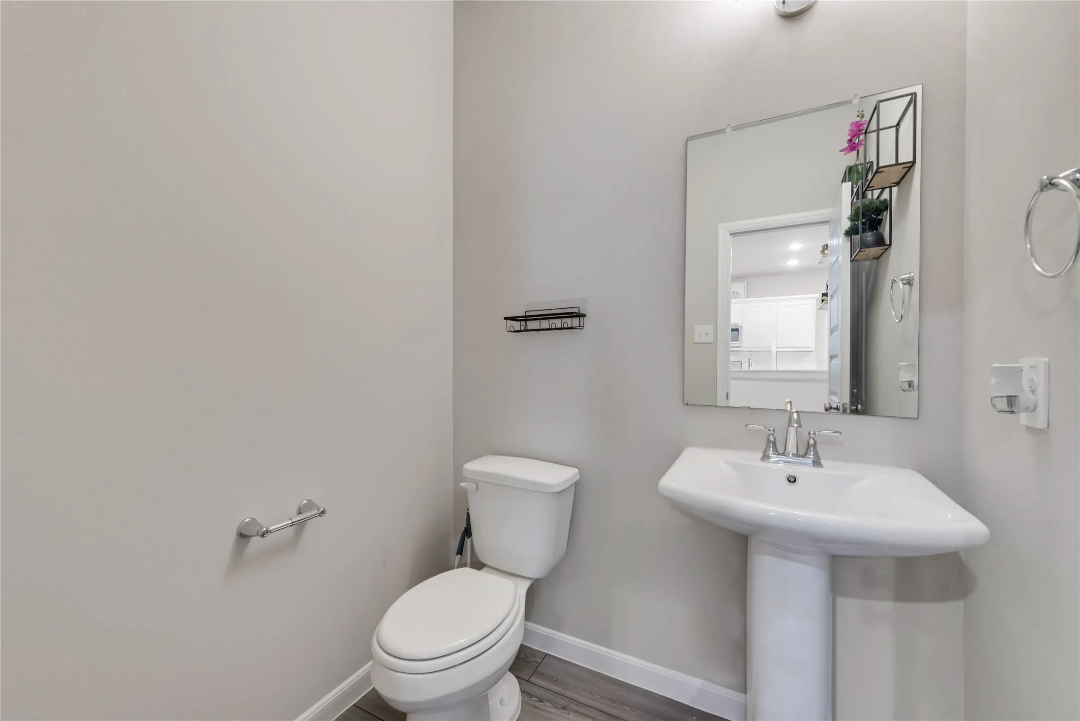 Bathroom featuring toilet, wood finished floors, a sink, and baseboards