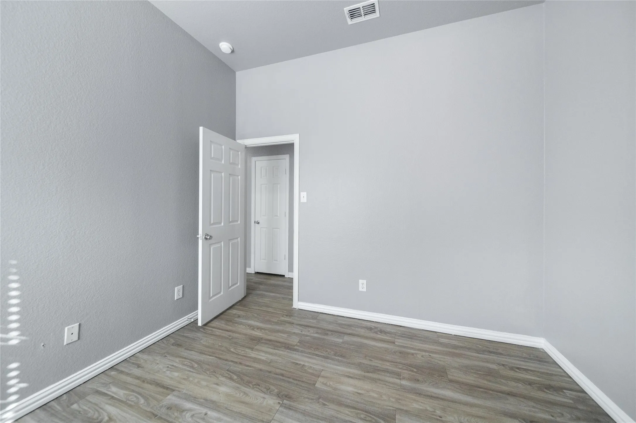 Interior room featuring wood-finish flooring, white baseboards, and light gray walls