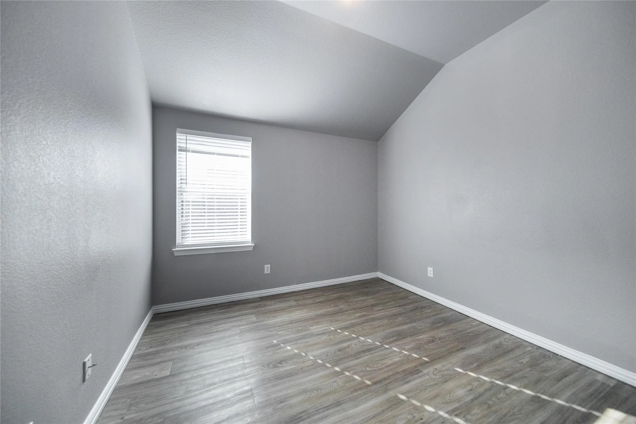 Room featuring contemporary gray walls, wood-finish flooring, and a window with white blinds