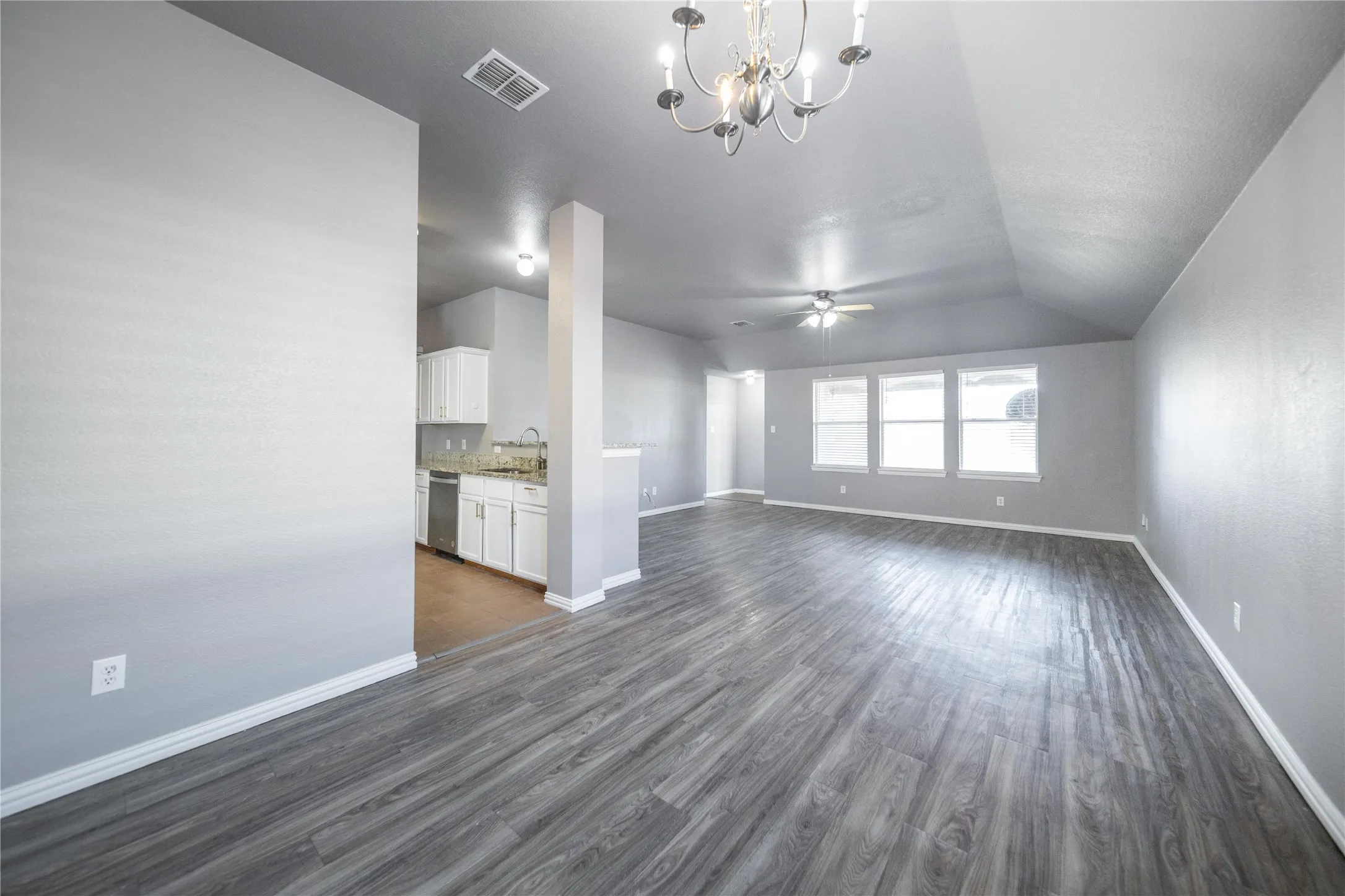 Open-concept living area with wood-finish flooring and a vaulted ceiling
