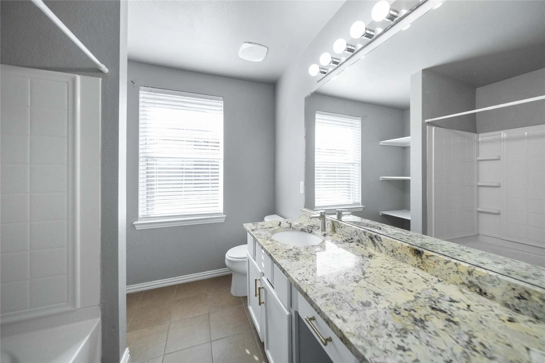 Bathroom featuring a double vanity with stone countertop, dual undermount sinks, and chrome faucets
