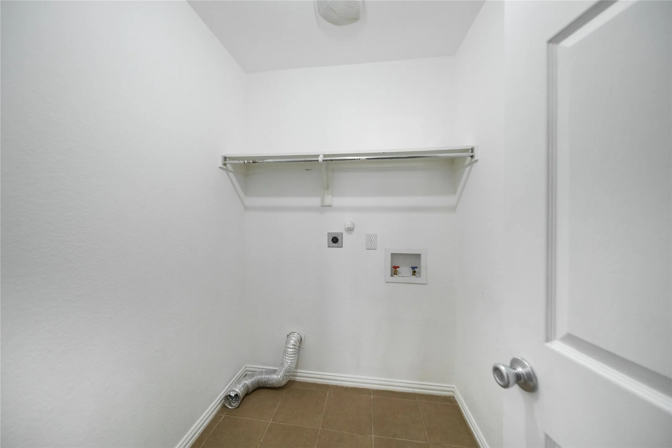 Dedicated laundry area featuring a built-in shelving unit, utility hookups, and tiled flooring