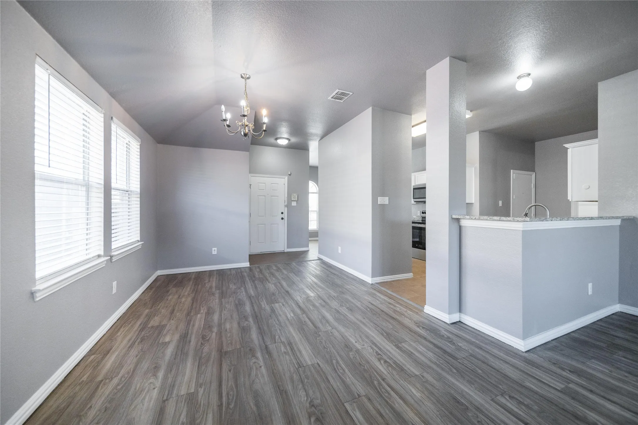 Spacious open-concept interior featuring wood-finish flooring, neutral gray walls, and white trim throughout
