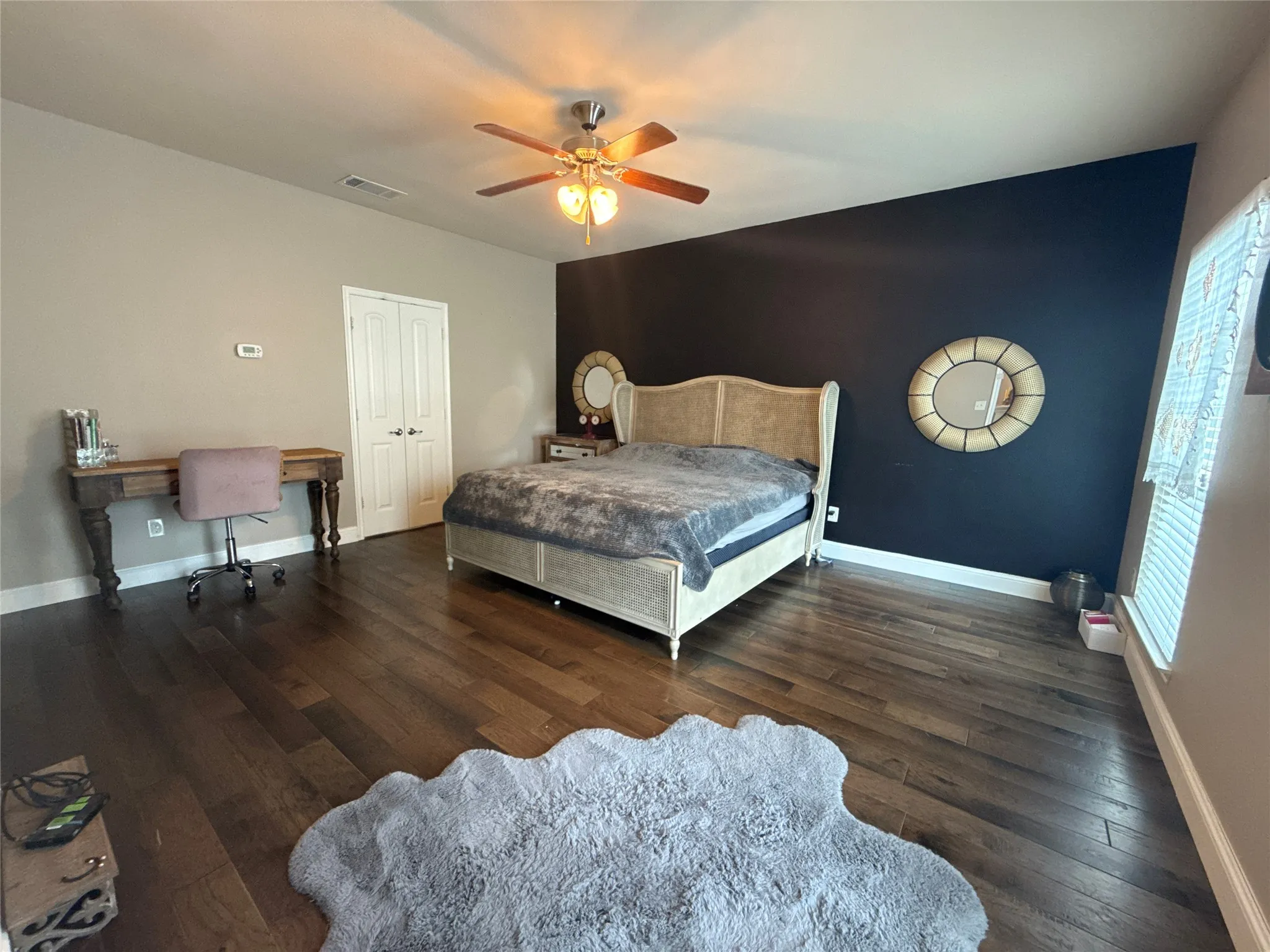 Spacious room featuring rich wood-finish flooring and a ceiling fan with integrated lighting