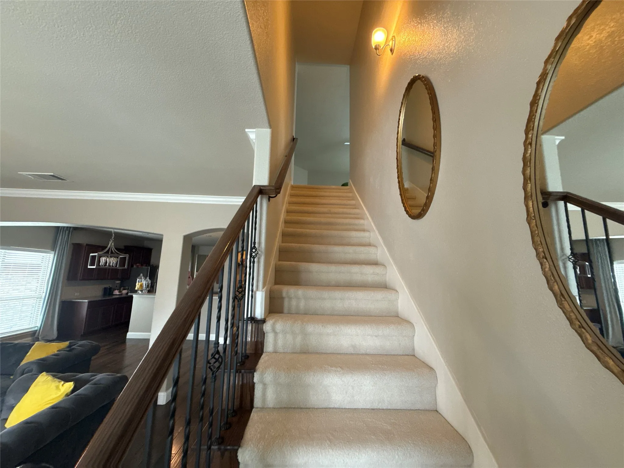 Carpeted staircase featuring a dark wood handrail and ornate wrought iron balusters