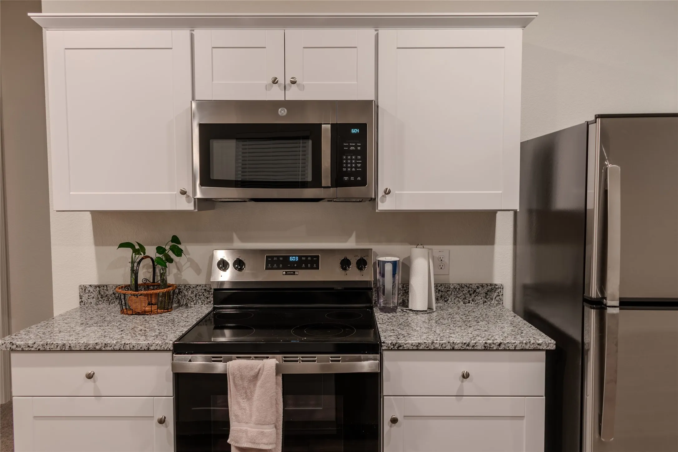Kitchen with light stone counters, white cabinets, and appliances with stainless steel finishes