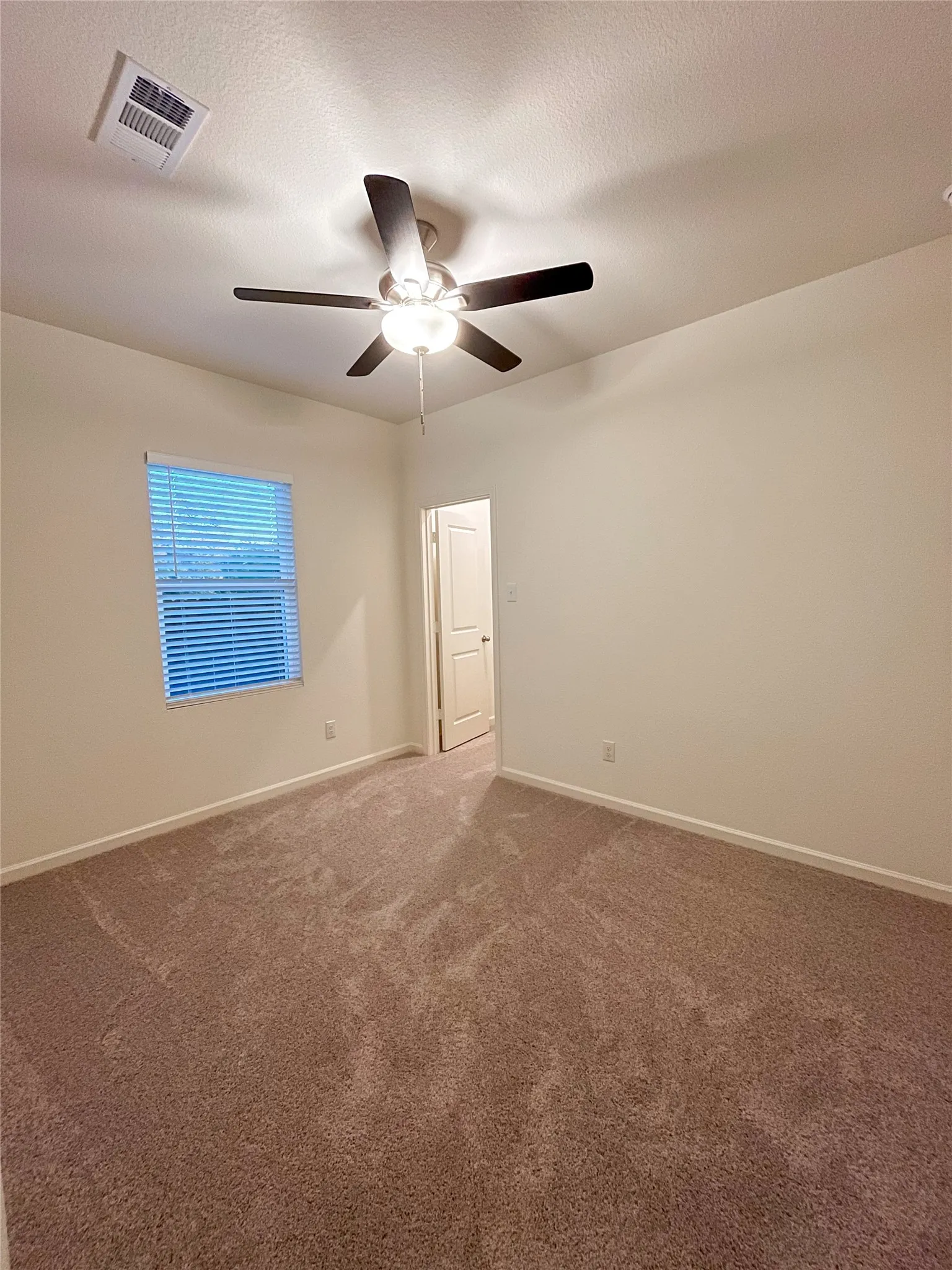 Spare room featuring carpet flooring, ceiling fan, and a textured ceiling
