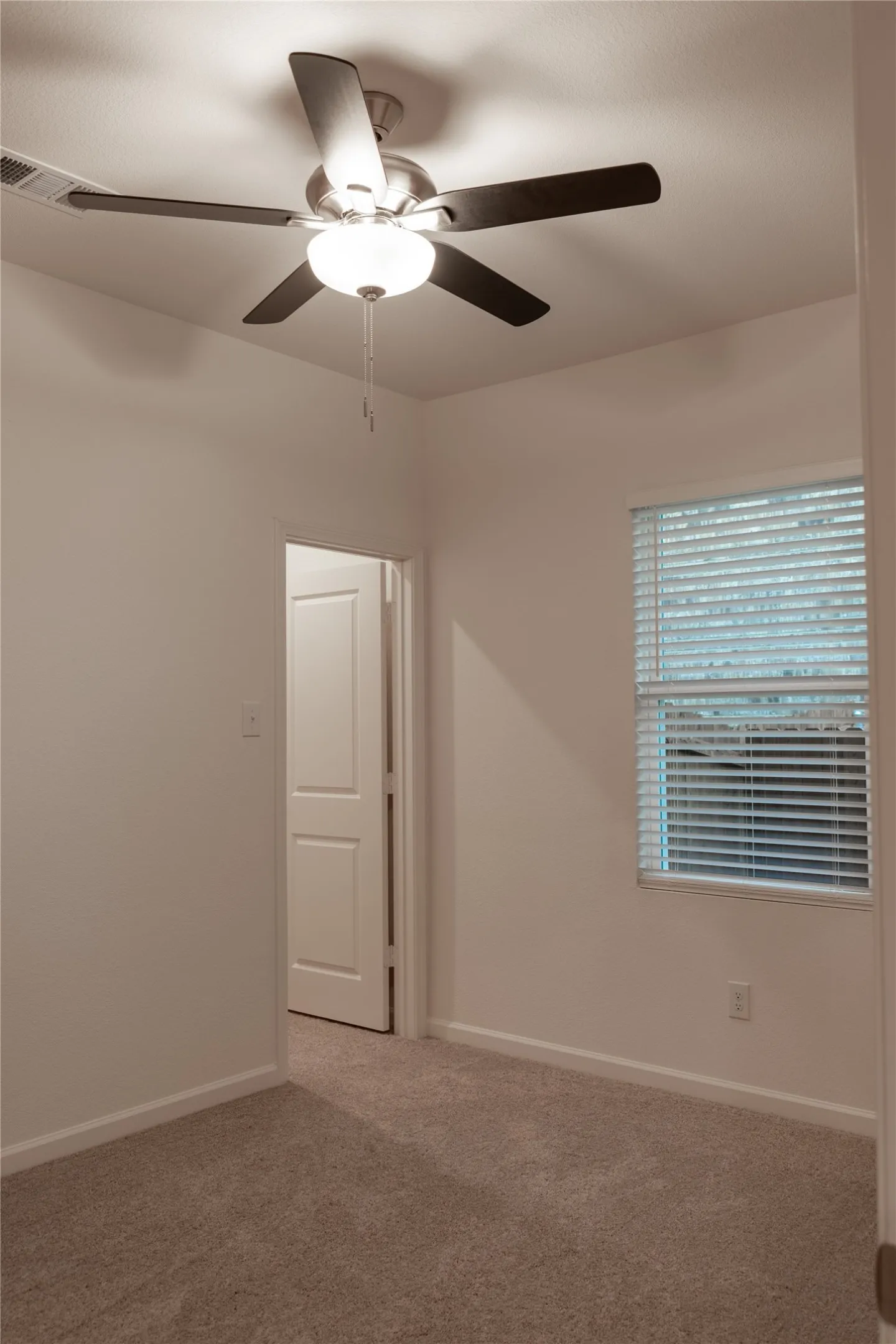 Carpeted empty room featuring ceiling fan