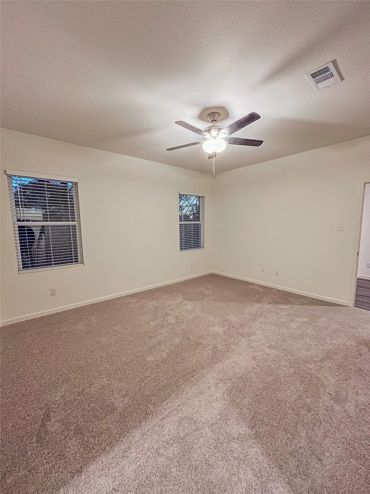 Carpeted empty room with ceiling fan and a textured ceiling