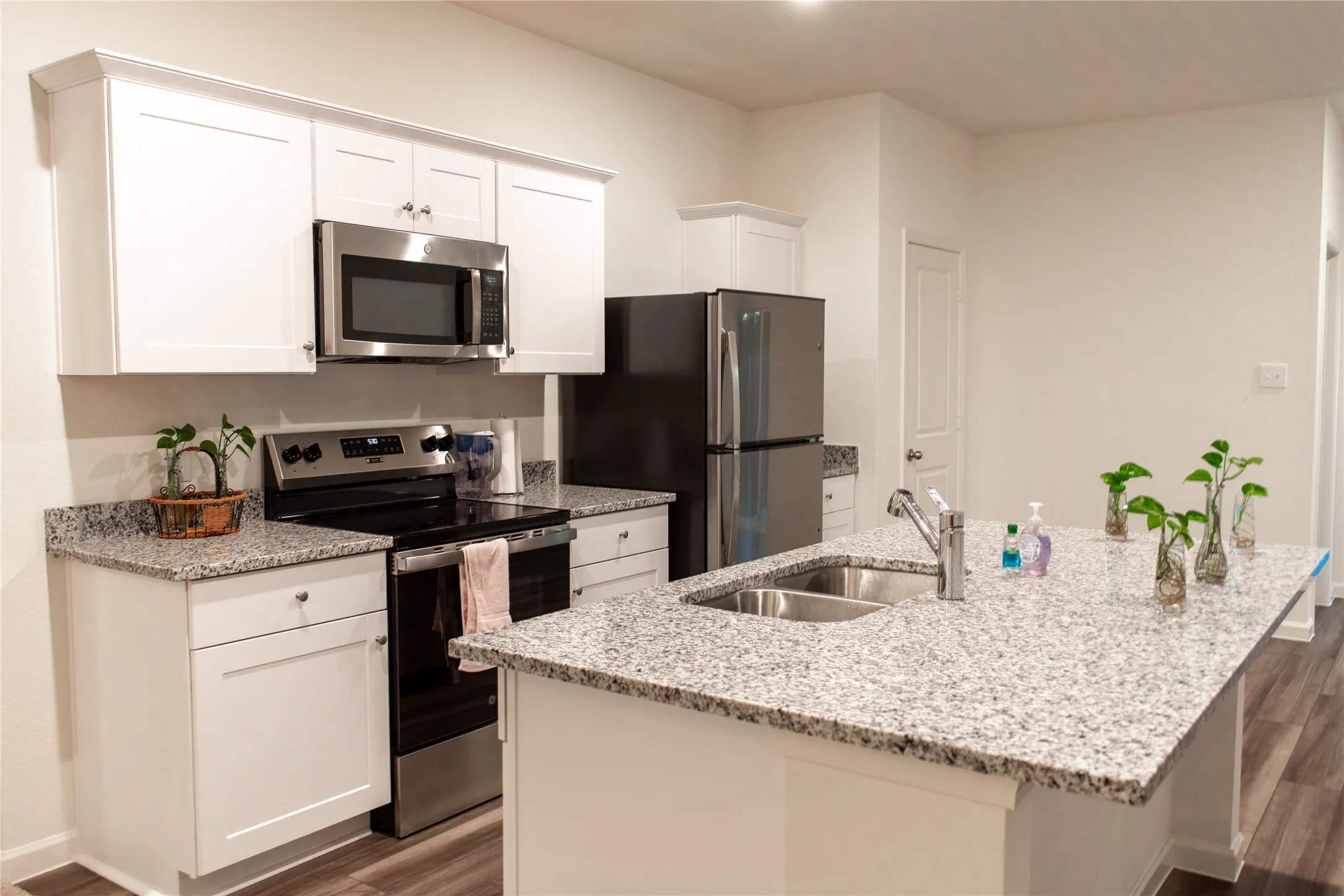 Kitchen with sink, white cabinets, stainless steel appliances, and a center island with sink
