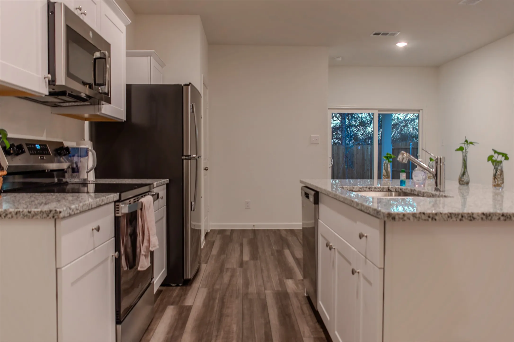 Kitchen featuring light stone countertops, appliances with stainless steel finishes, dark hardwood / wood-style flooring, sink, and white cabinetry