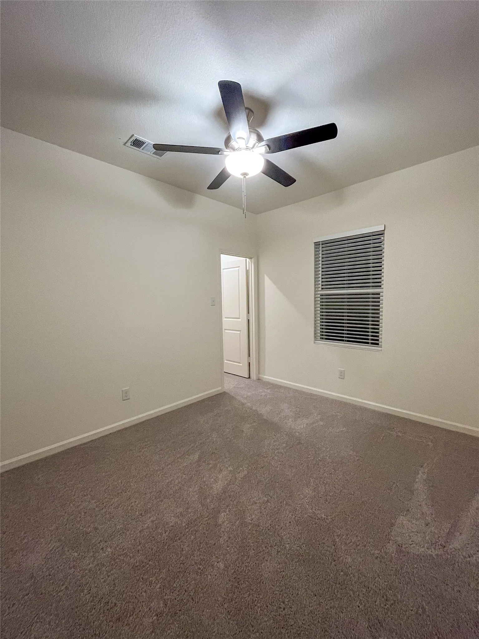 Carpeted spare room featuring a textured ceiling and ceiling fan